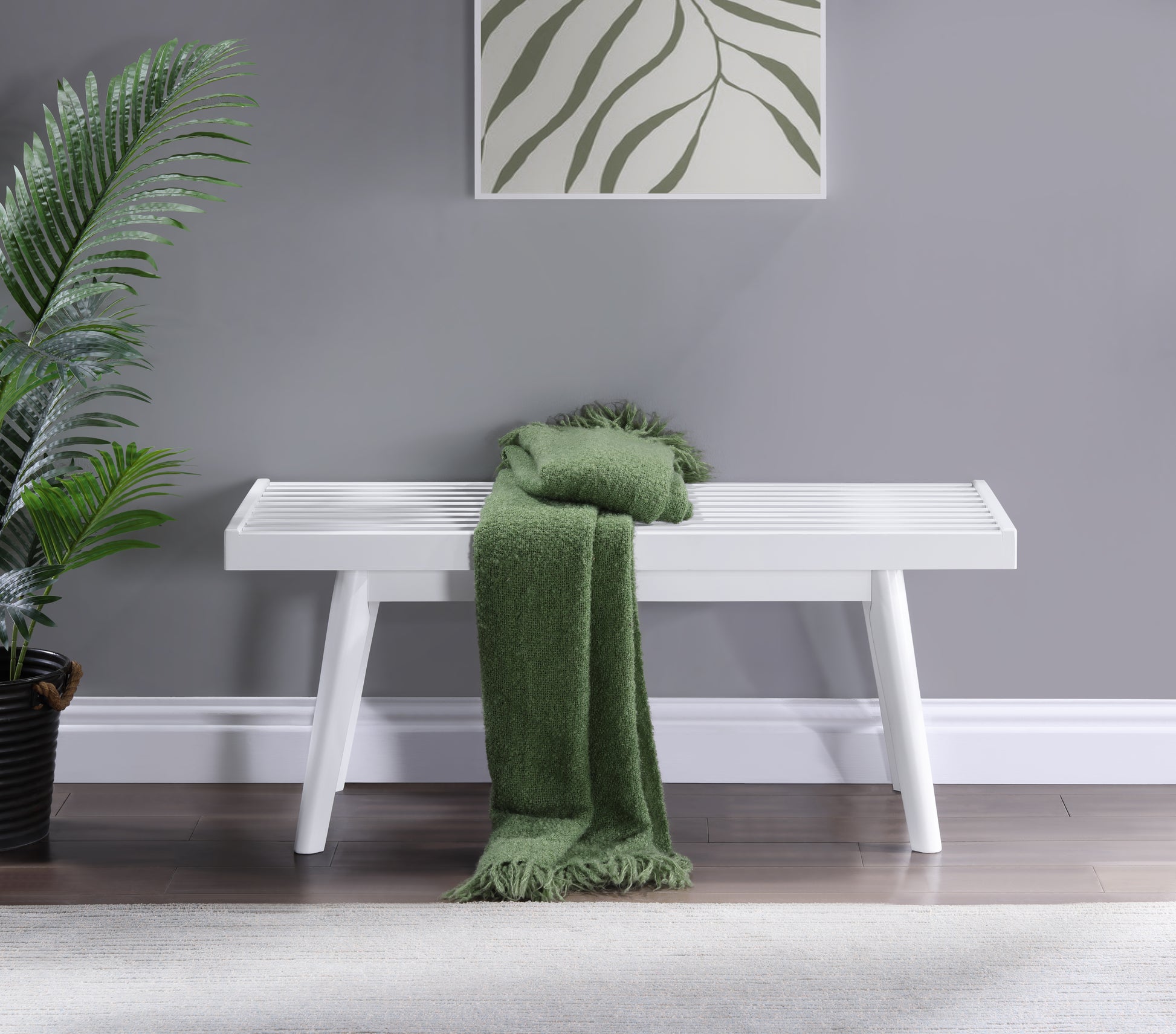 White slatted bench with plush green throw blanket