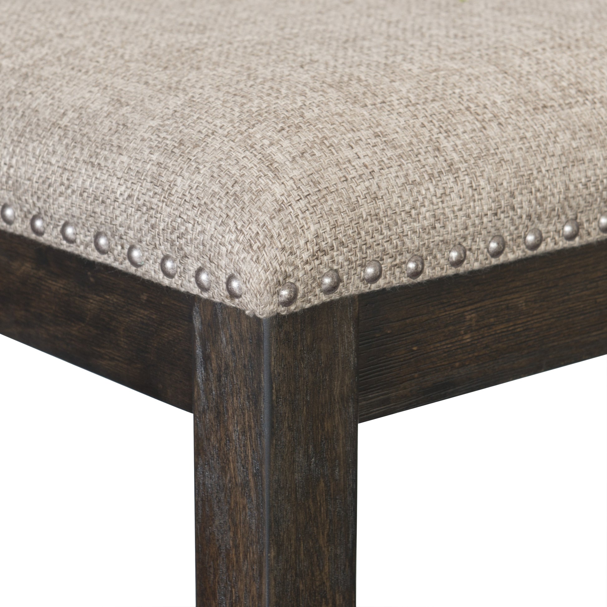 Closeup of neutral textured fabric seat with decorative nailhead trim on dark wood