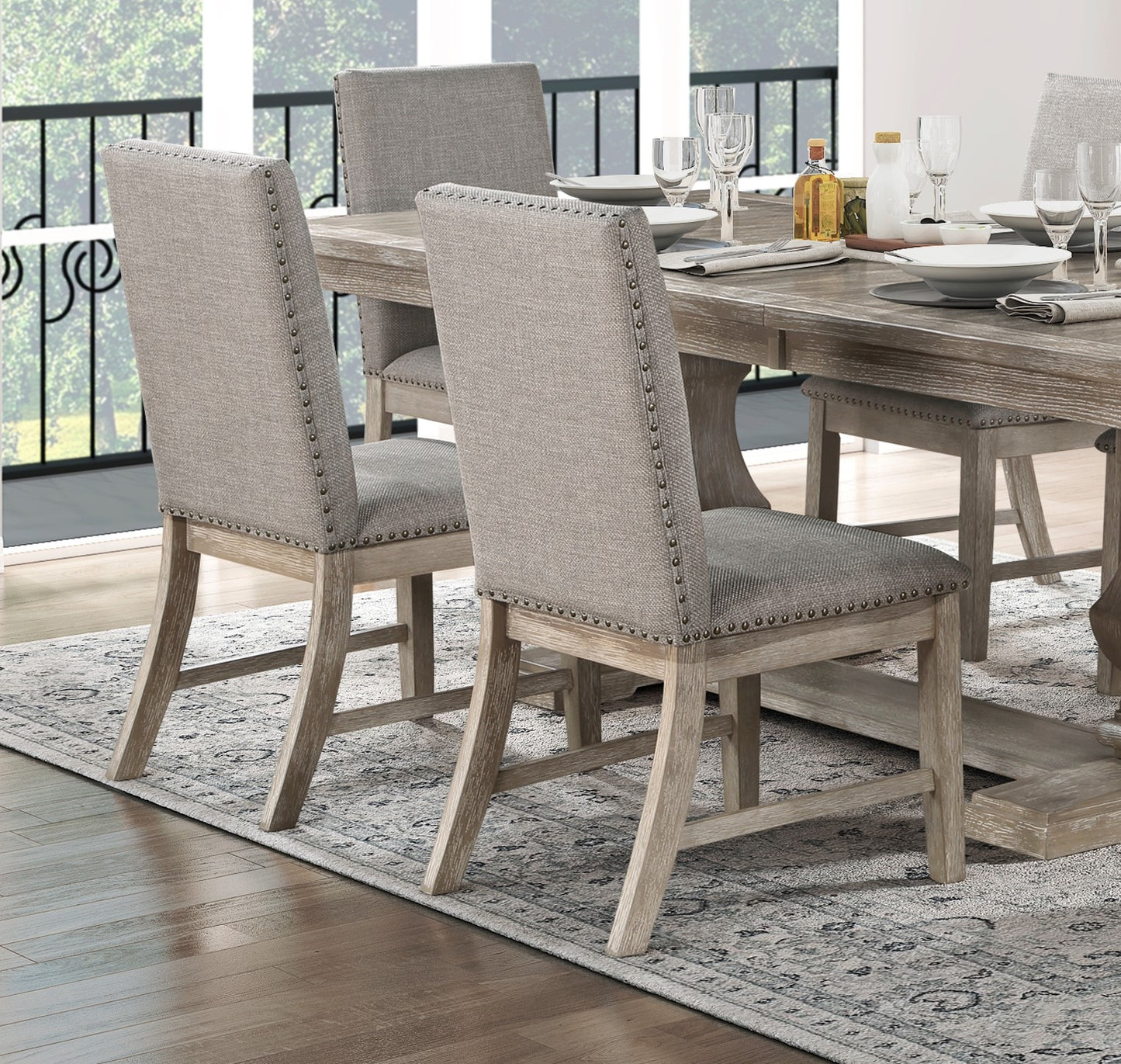 Gray upholstered dining chair with nailhead trim and distressed wood legs
