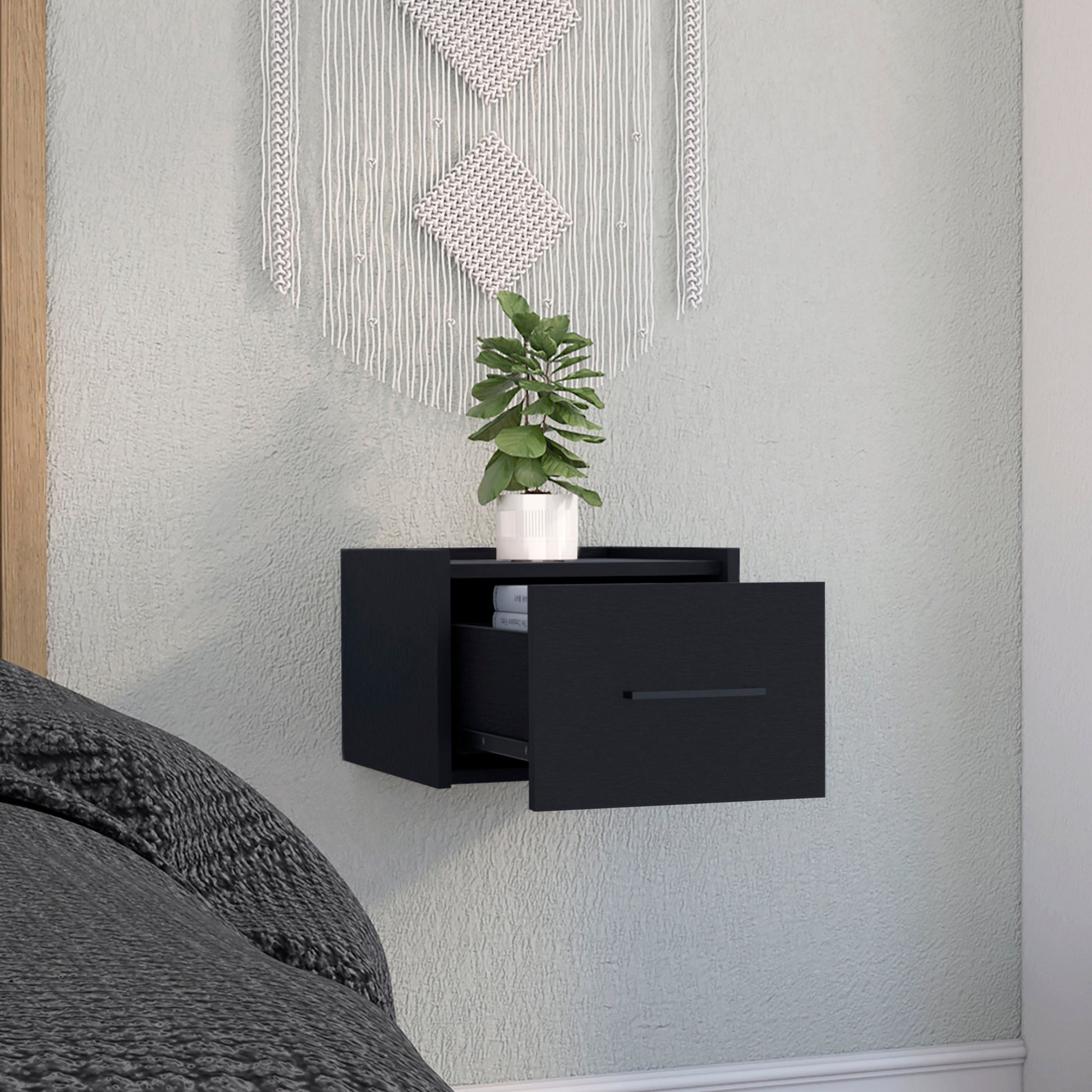 Sleek black floating nightstand with one drawer open showing books inside