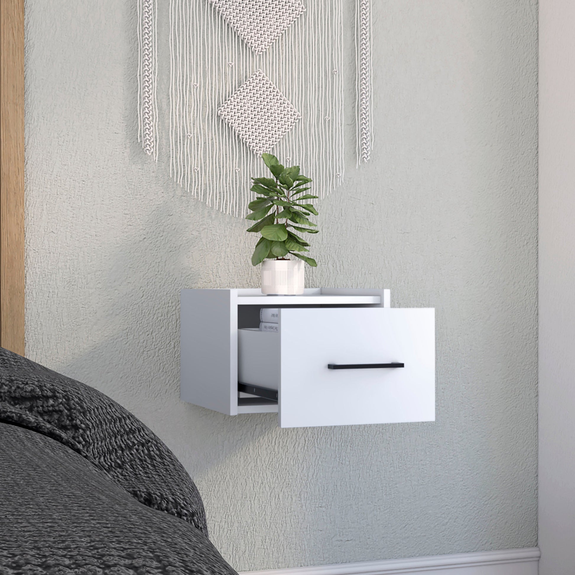 Modern white wallmounted nightstand with open shelf and black handle a plant on top