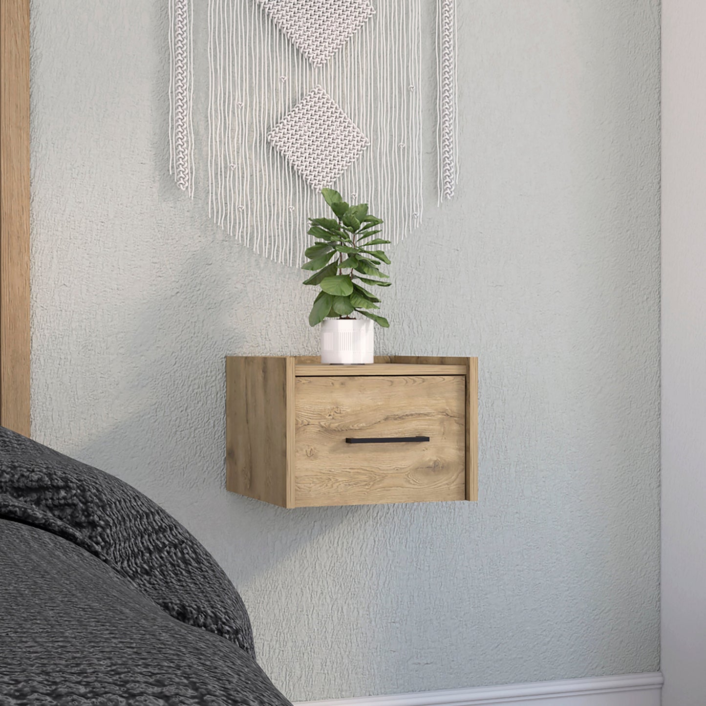 Floating wooden nightstand with black handle next to bed