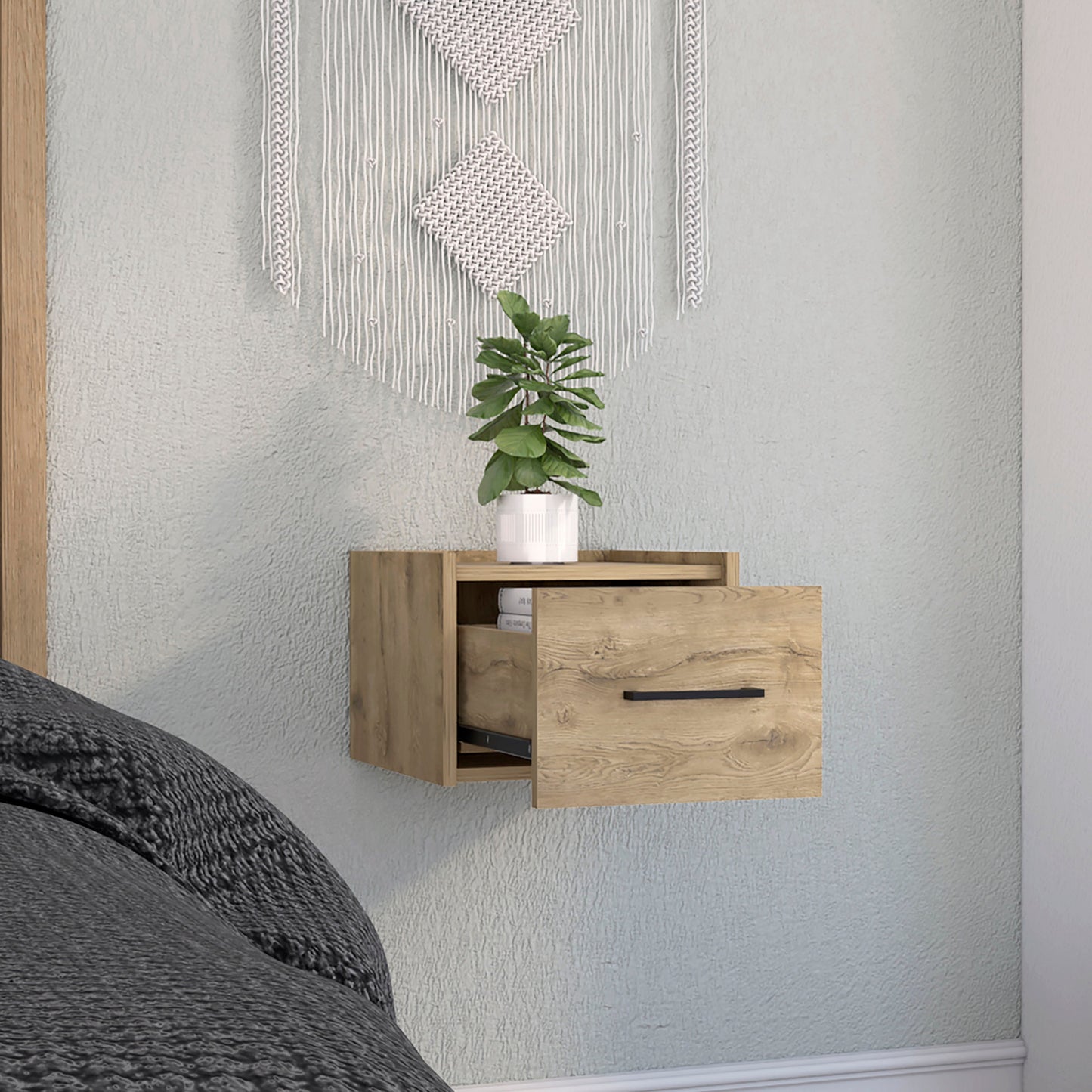 Light oak floating nightstand with one drawer holding books and a plant