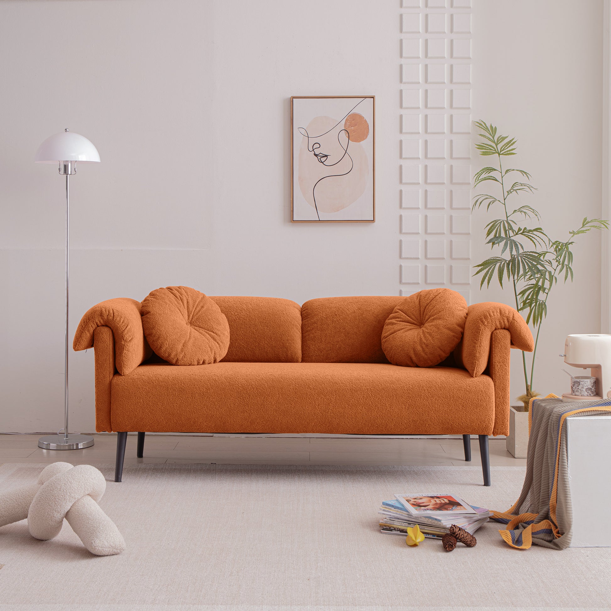 Orange boucle sofa with two round throw pillows and black legs