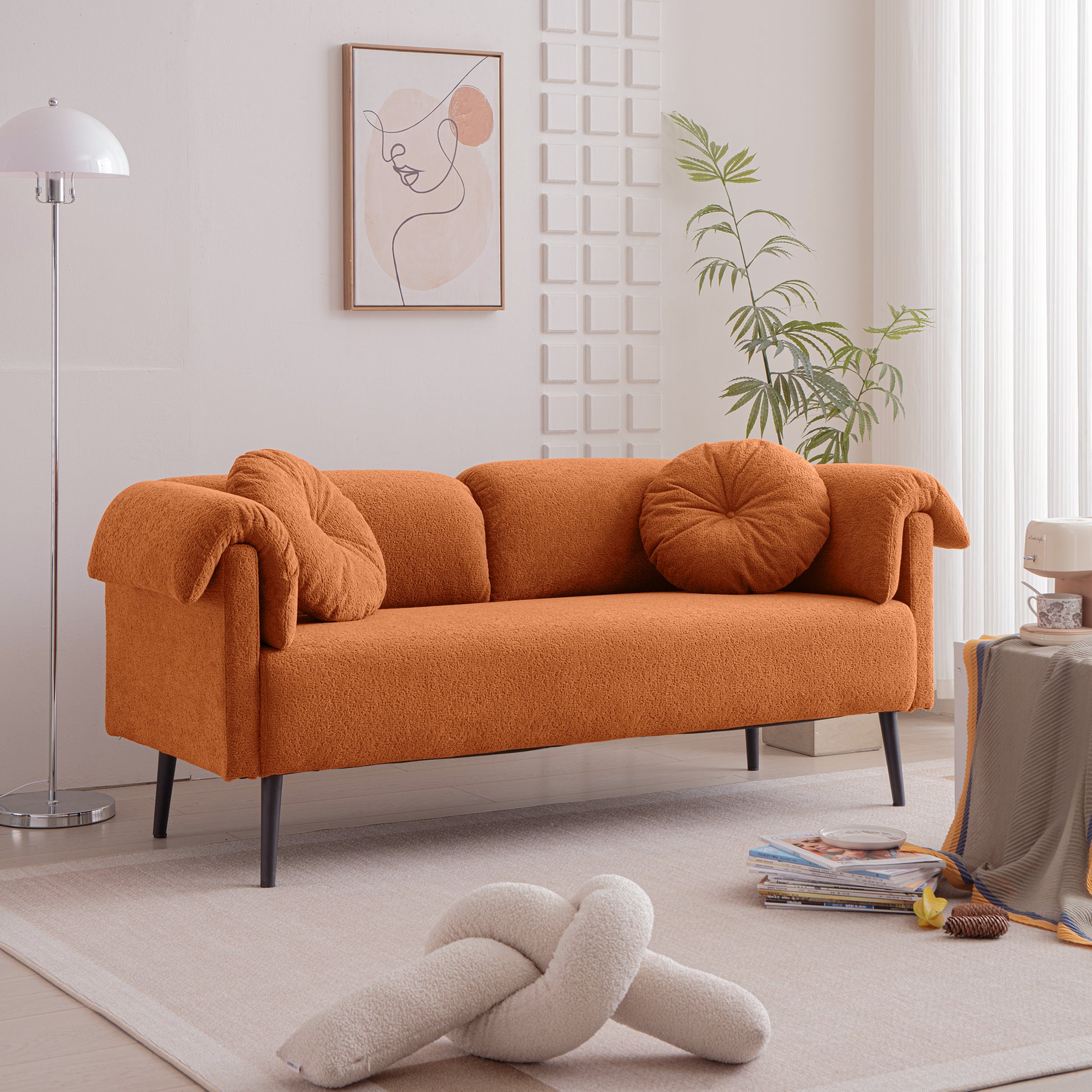Orange boucle fabric sofa with two accent pillows and black legs