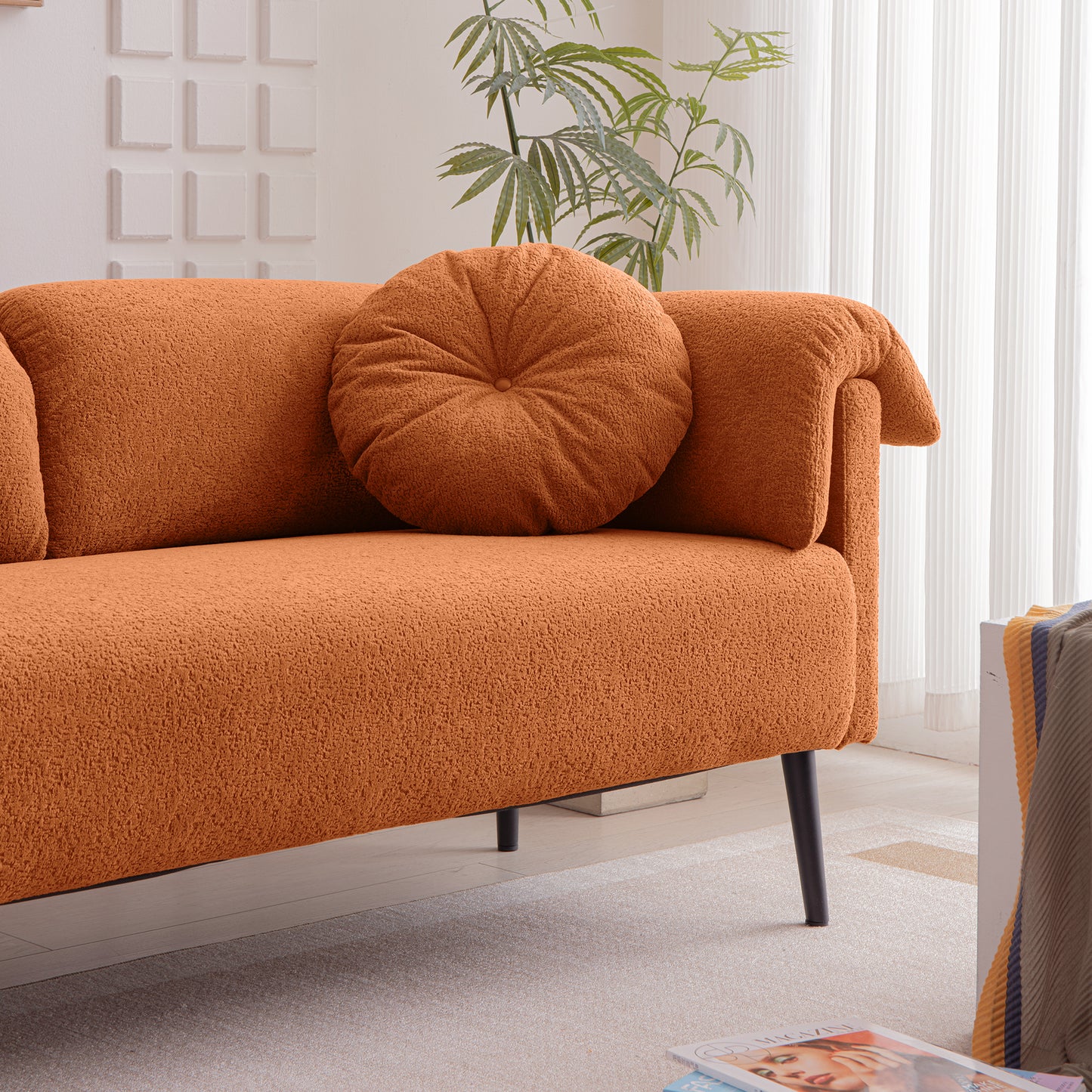 Orange textured boucle sofa with a round decorative pillow