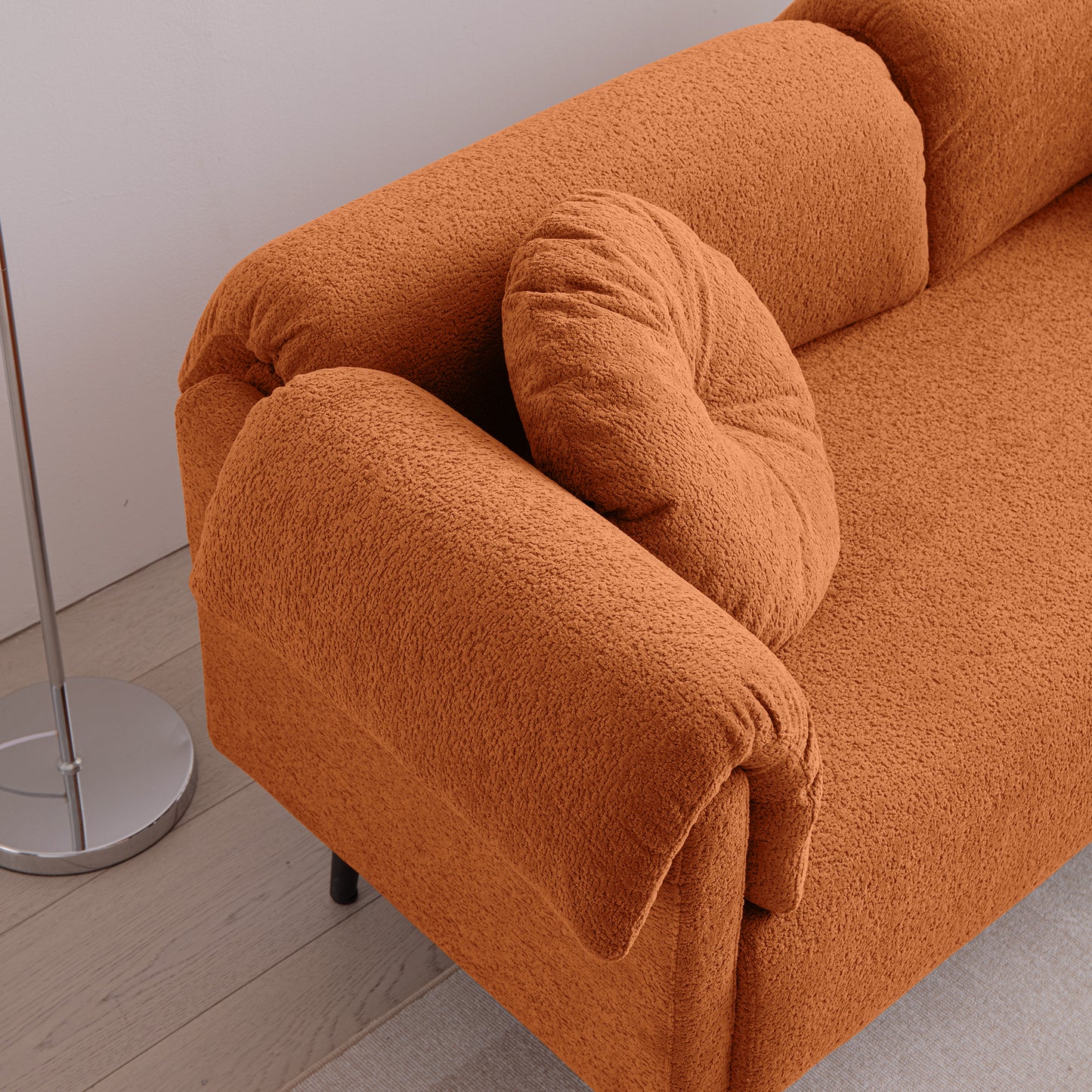 Orange boucle fabric sofa with a rounded armrest and a plush cushion
