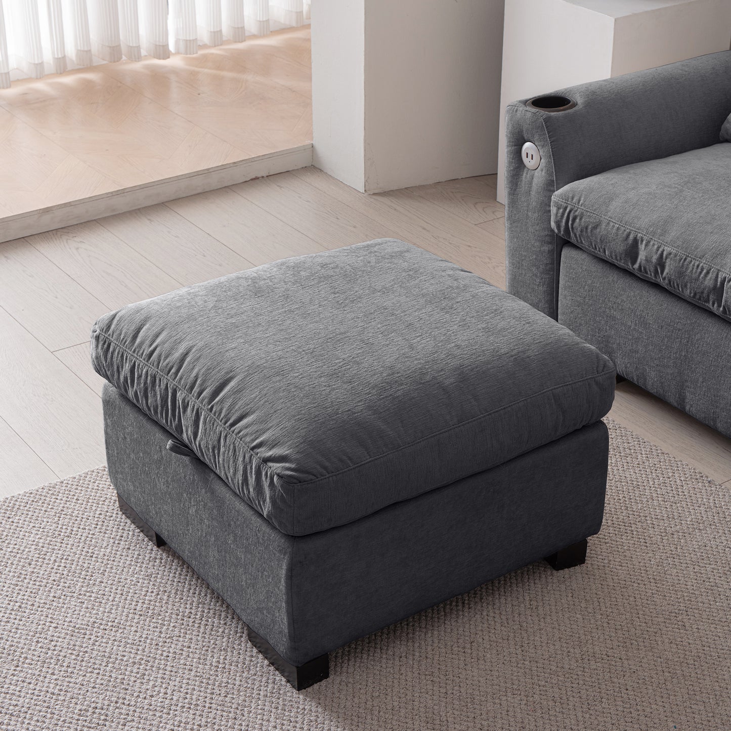 Plush charcoal grey fabric ottoman with a deep cushioned top for comfortable seating