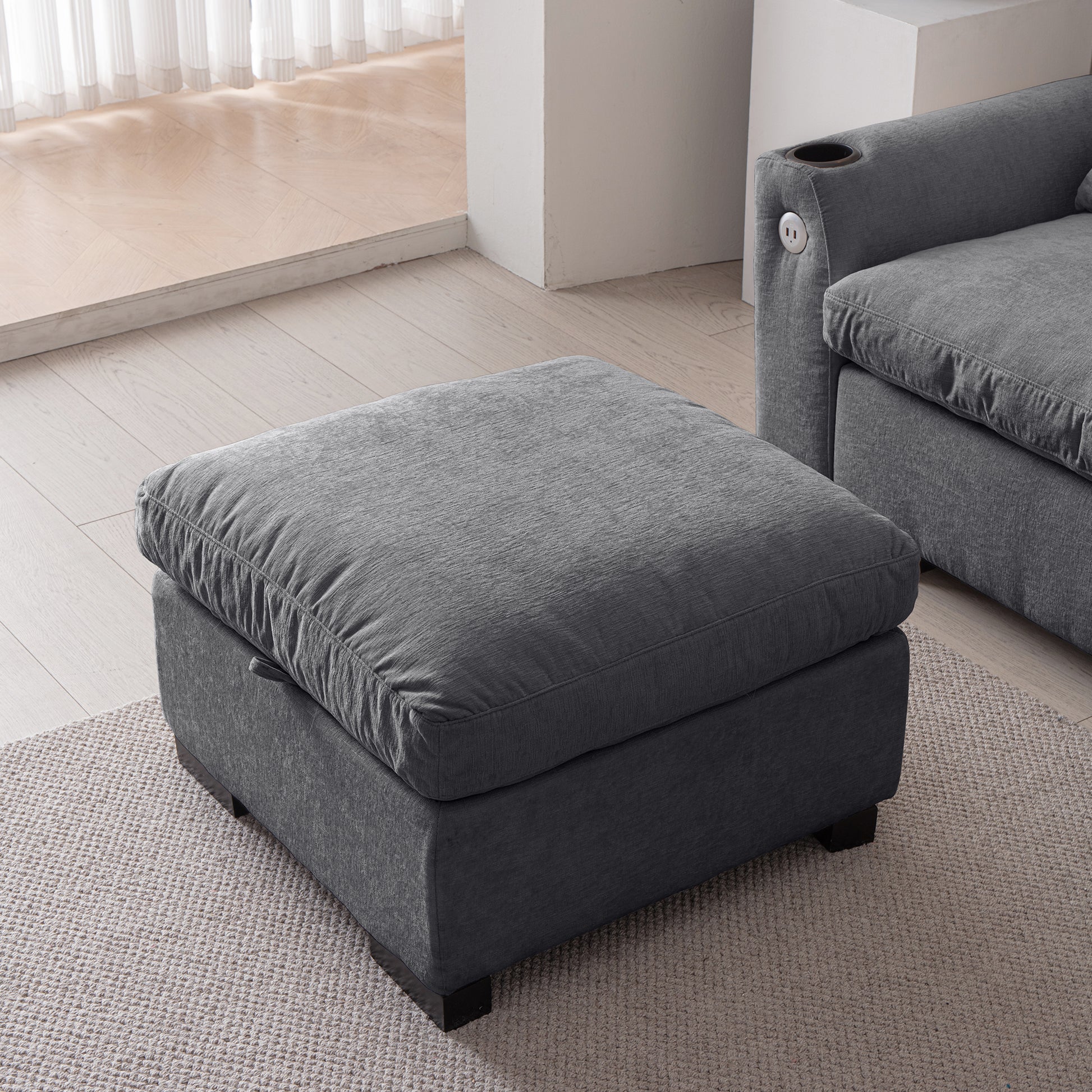 Plush charcoal grey fabric ottoman with a deep cushioned top for comfortable seating