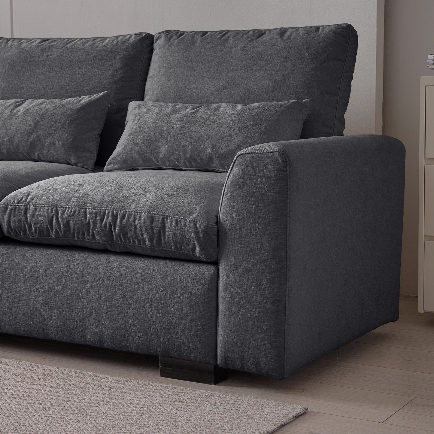 Deep charcoal grey fabric sofa with plush oversized cushions and lumbar pillow