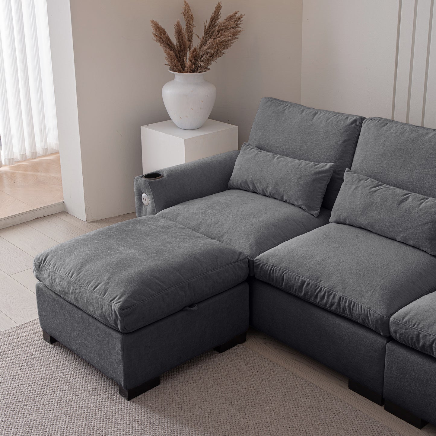 Dark grey fabric sectional sofa with plush cushions and an ottoman