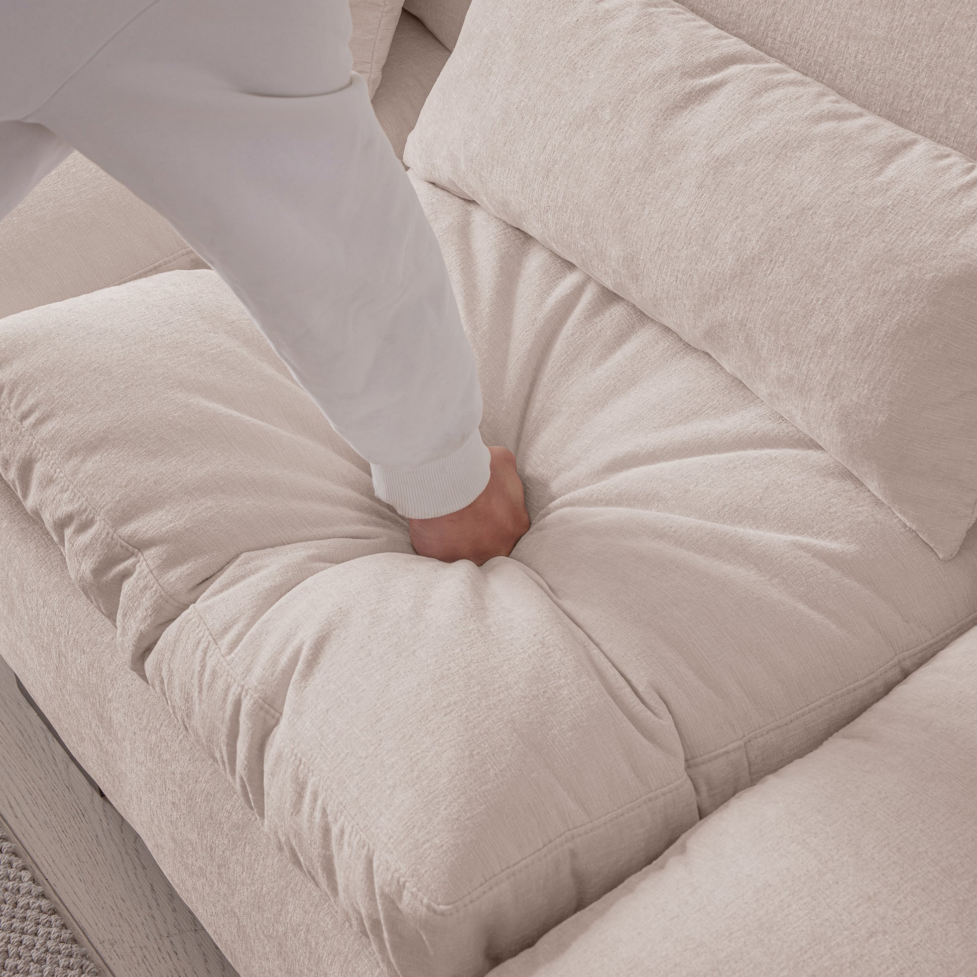 Closeup of a hand testing the plush comfort of a beige linen sofa cushion