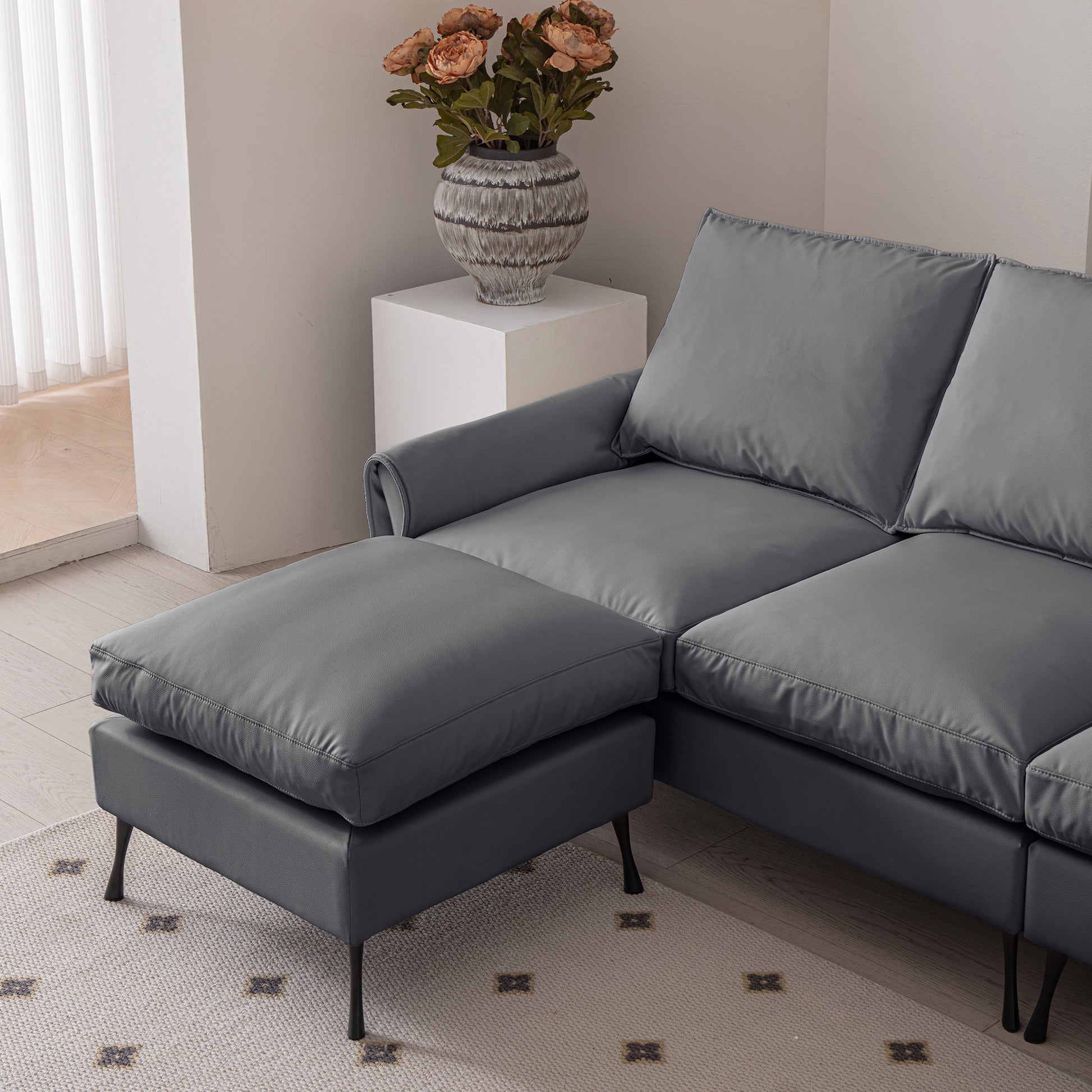 Gray leather sectional sofa with a chaise lounge and ottoman perfect for modern living rooms