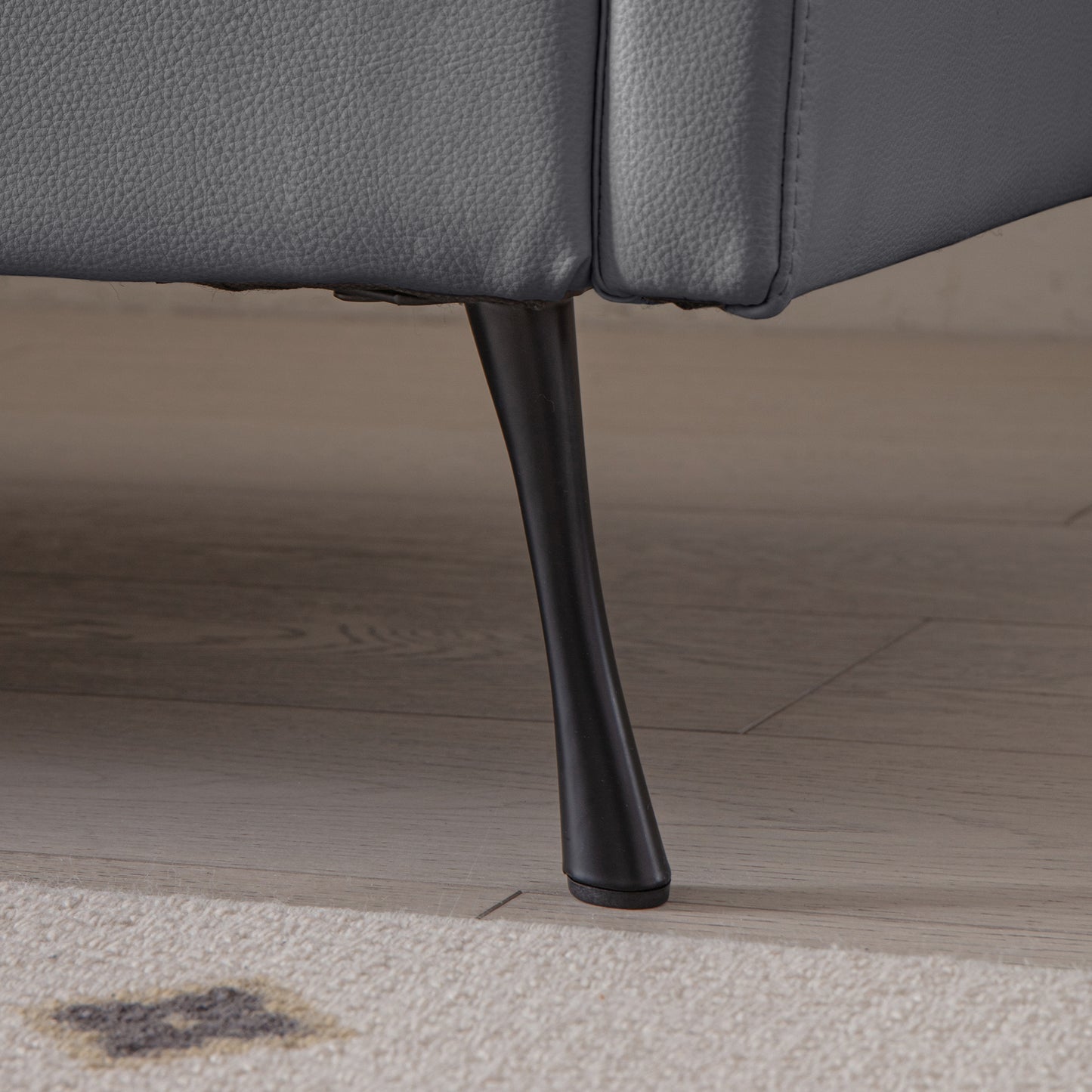 Closeup of a grey faux leather sofa leg showcasing its sleek modern design
