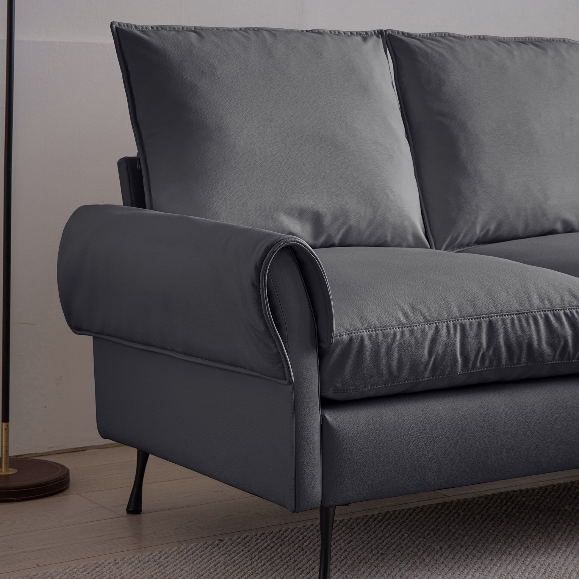 Modern dark gray faux leather sofa with plush cushions and elegant rolled arms