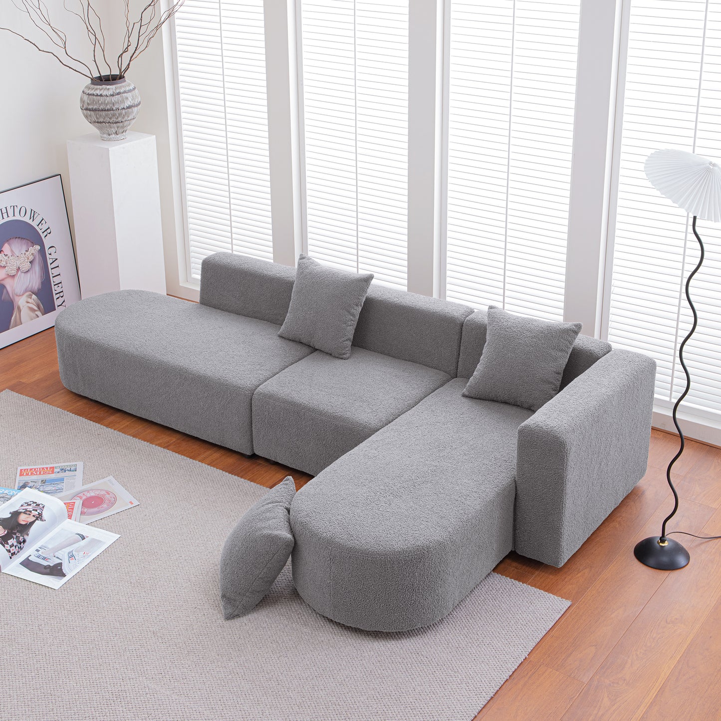 Gray modular sectional sofa with textured fabric includes loose pillows and ottoman for versatile seating
