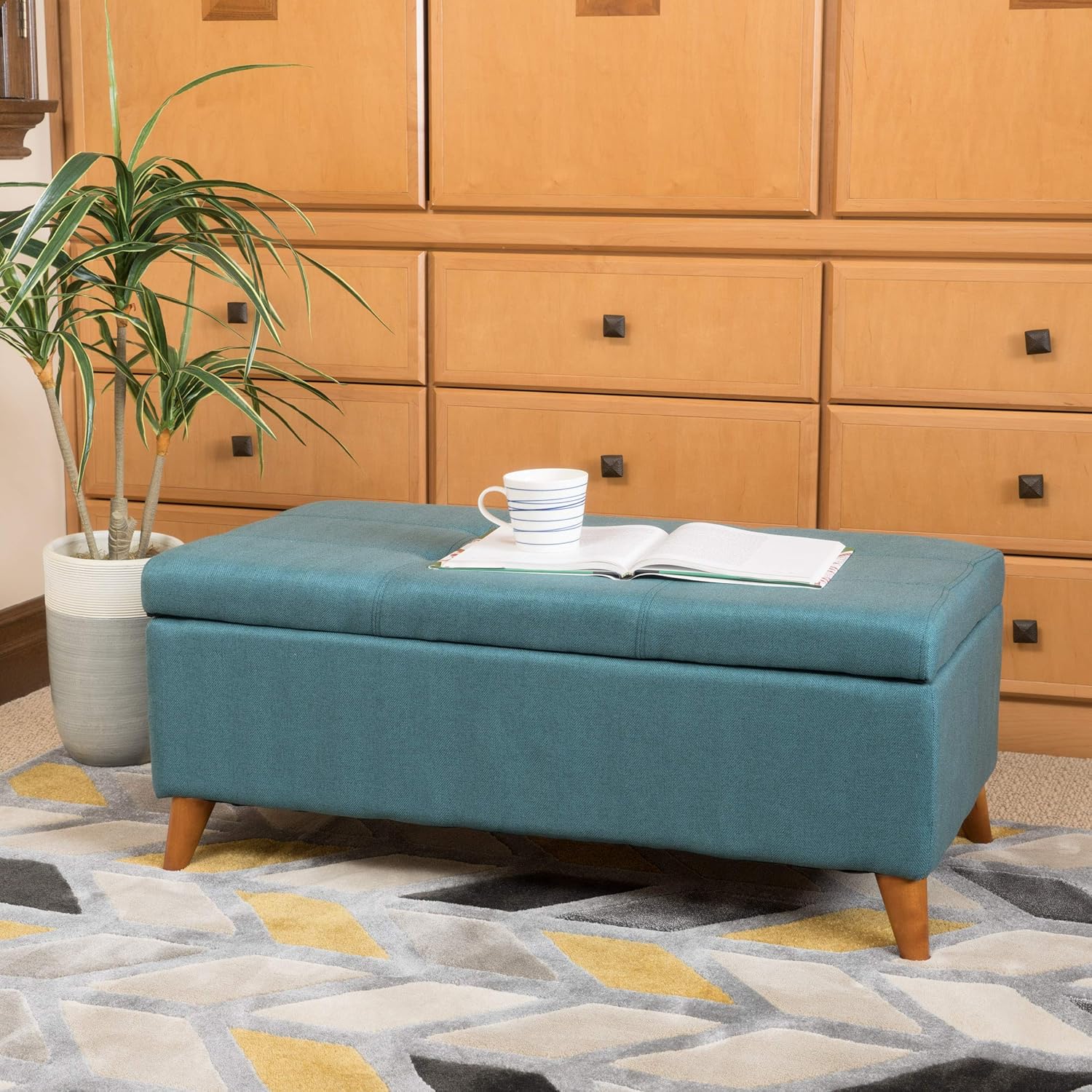 Teal upholstered storage ottoman with tufted lid and midcentury modern legs