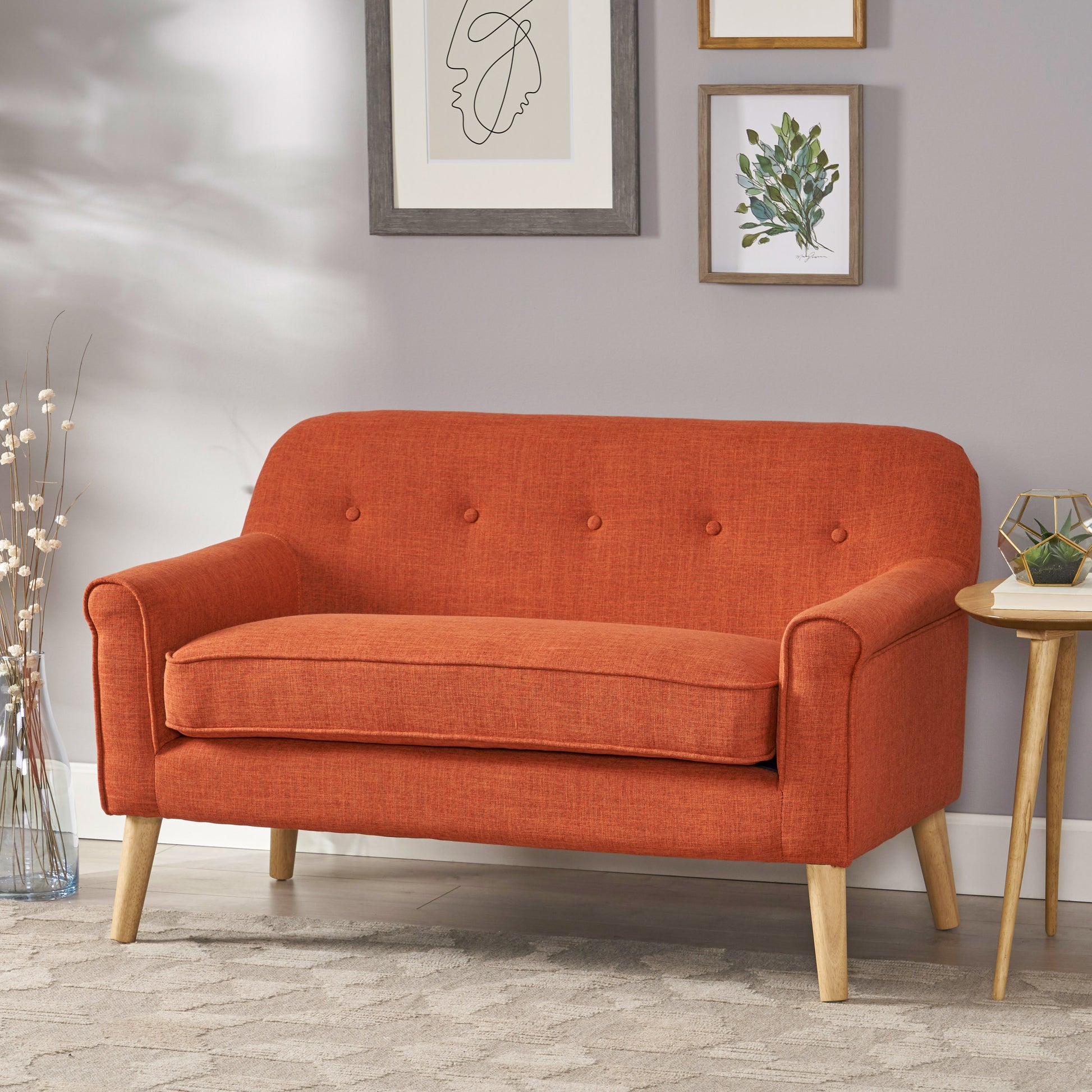 Orange upholstered loveseat with button tufting and wooden legs perfect for small living spaces