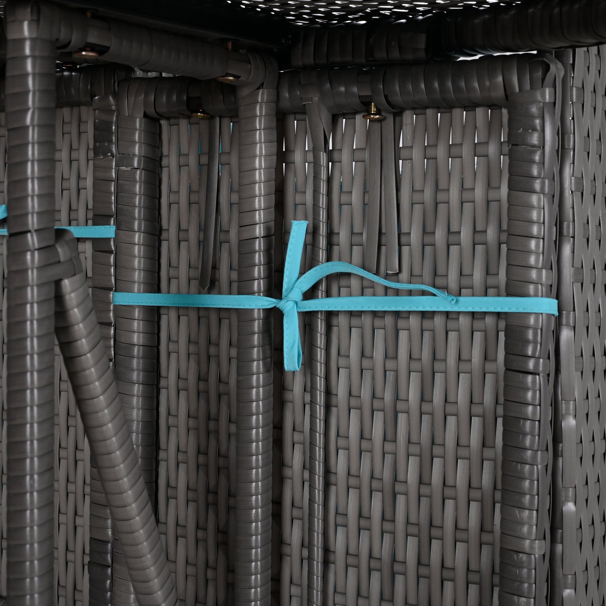 Close up of grey rattan weave with blue strap detail on furniture legs