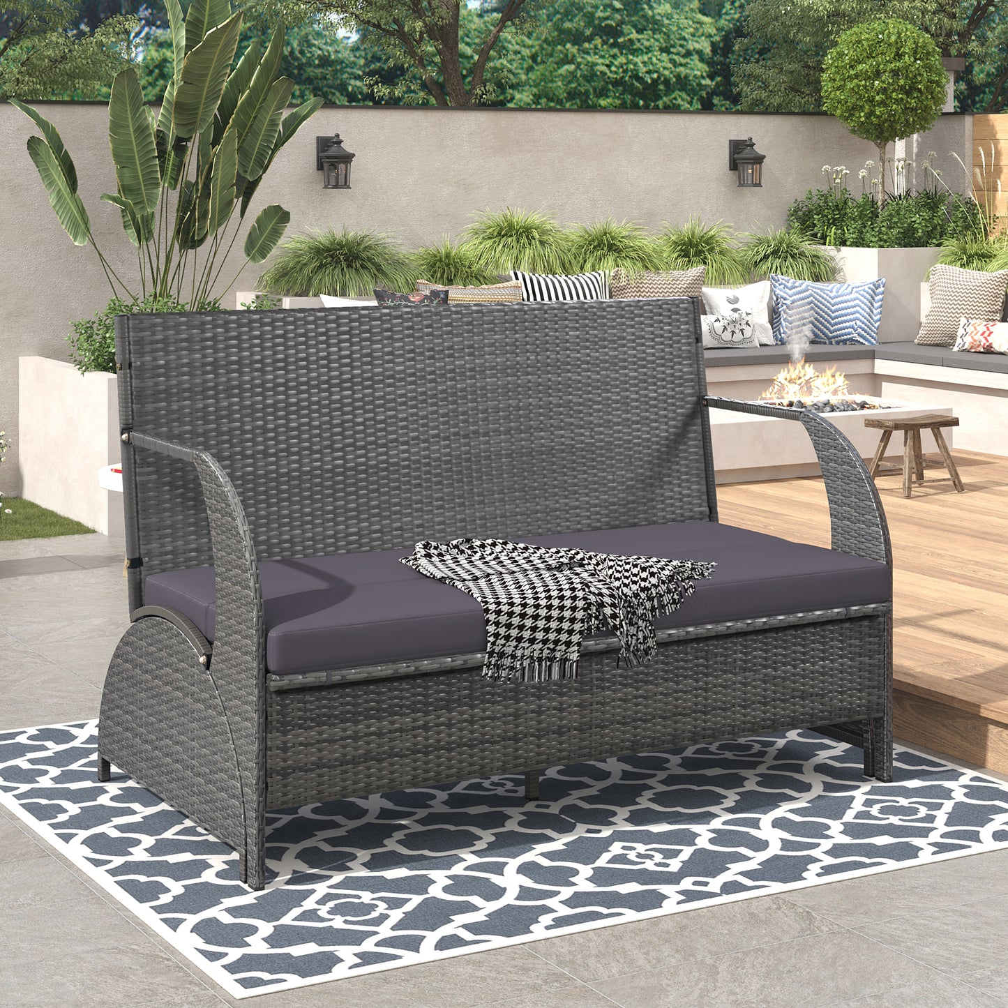 Gray wicker loveseat with dark gray cushions placed on an outdoor patio rug