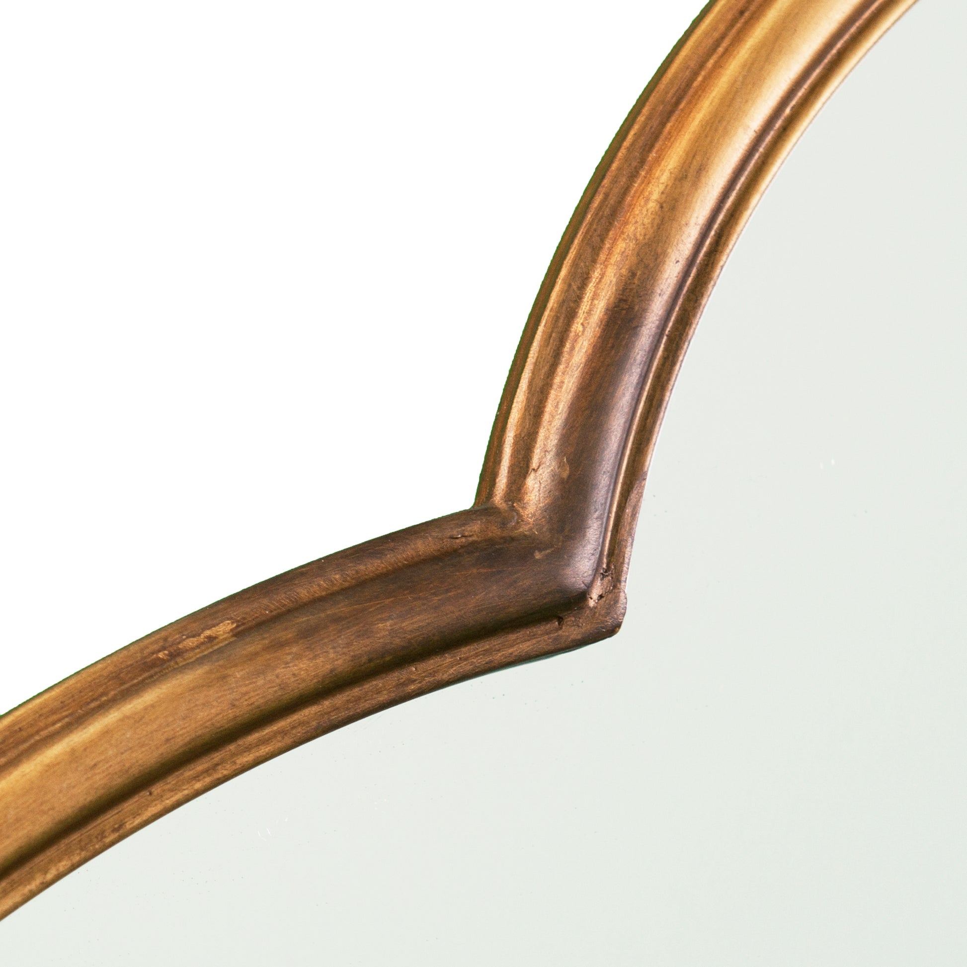 Closeup of ornate antique bronze mirror frame with subtle patina