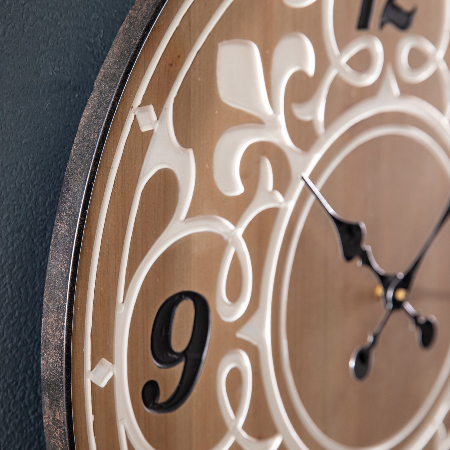 Closeup of a rustic wood wall clock with ornate white scrollwork and black hands