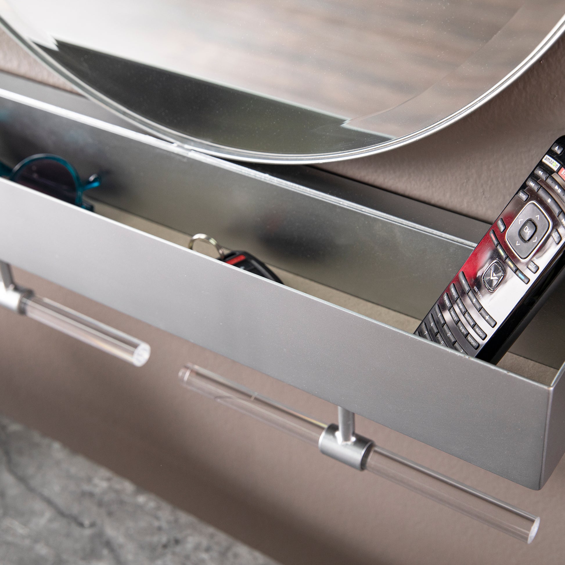 Sleek metal entryway shelf holding keys sunglasses and a TV remote for organized living