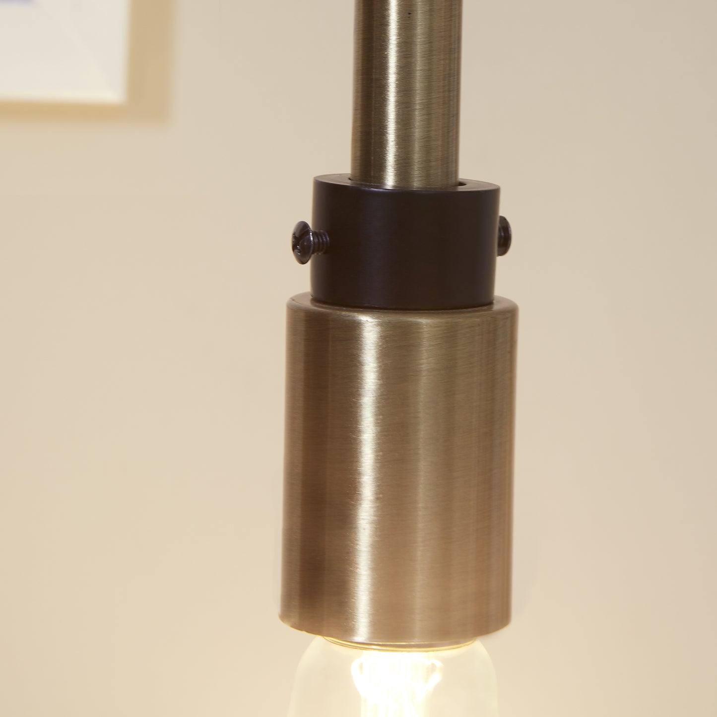Closeup of brushed brass pendant light fixture detail with dark accents