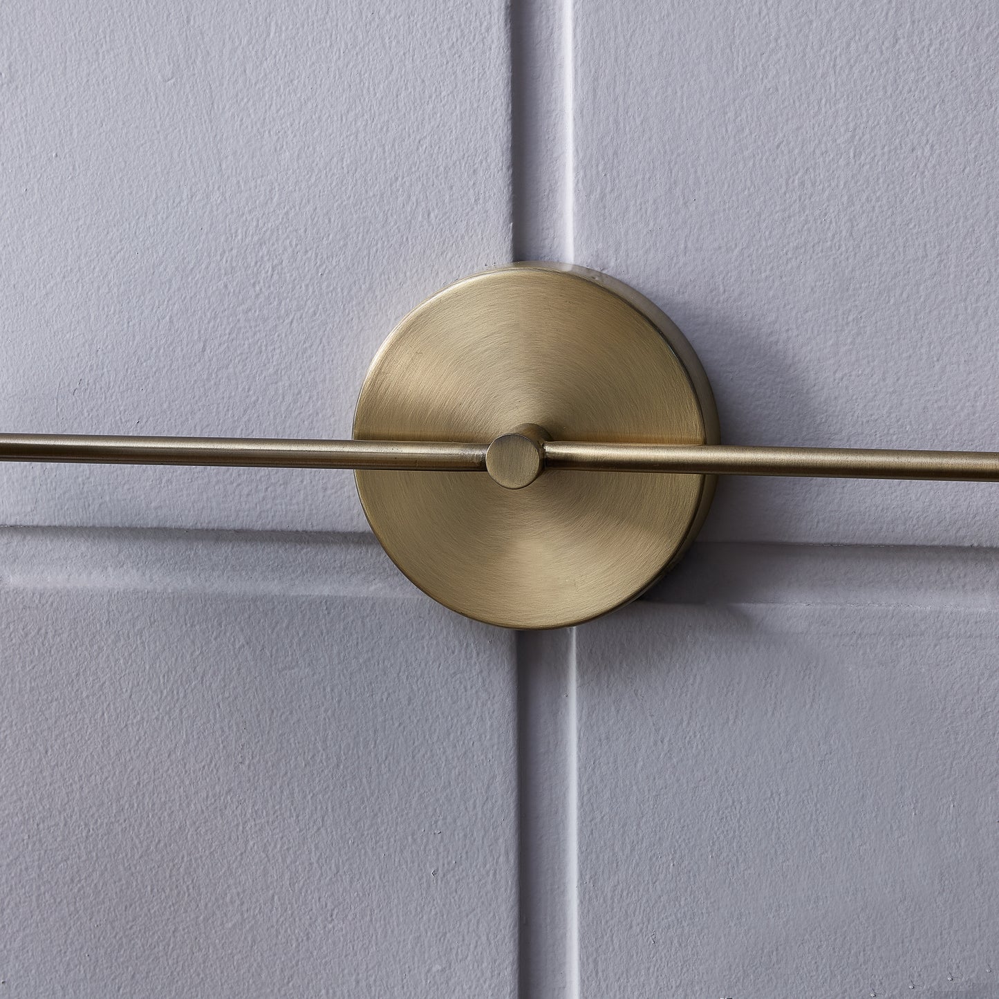 Brushed brass wall sconce with a circular backplate and horizontal arm