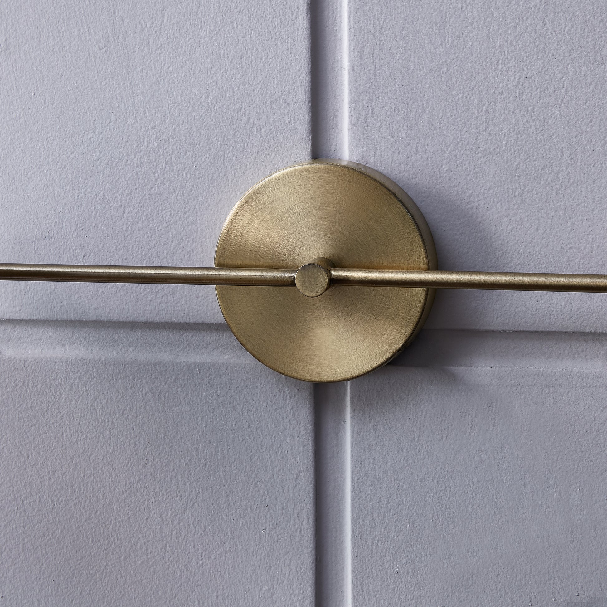 Brushed brass wall sconce with a circular backplate and horizontal arm