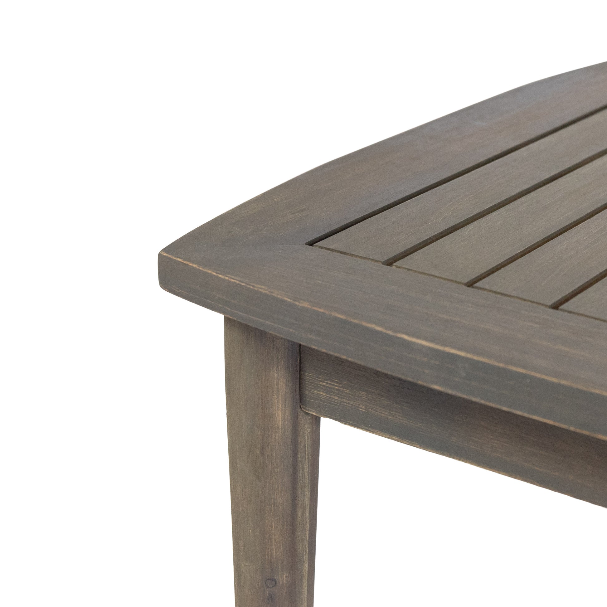 Closeup of a rustic grey wooden slatted patio table edge with a curved design