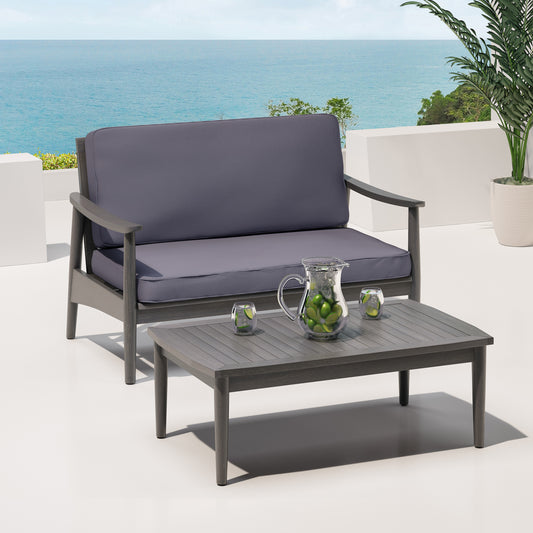 Modern grey outdoor sofa with plush cushions on a deck overlooking the ocean