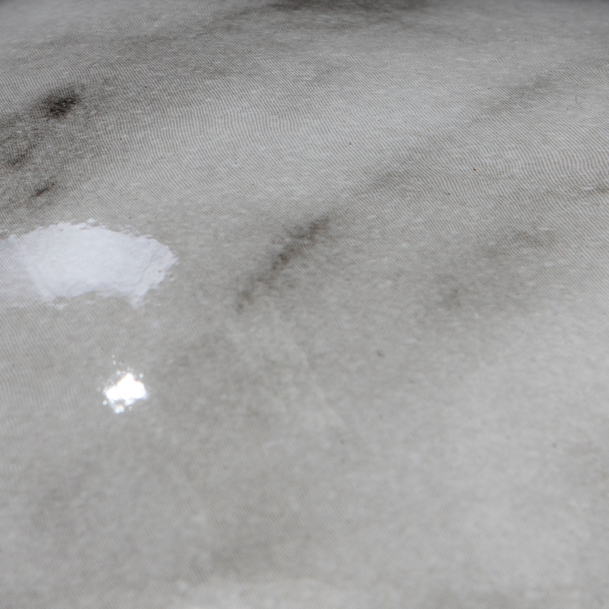 Closeup of grey textured fabric with subtle marblelike patterns and slight sheen