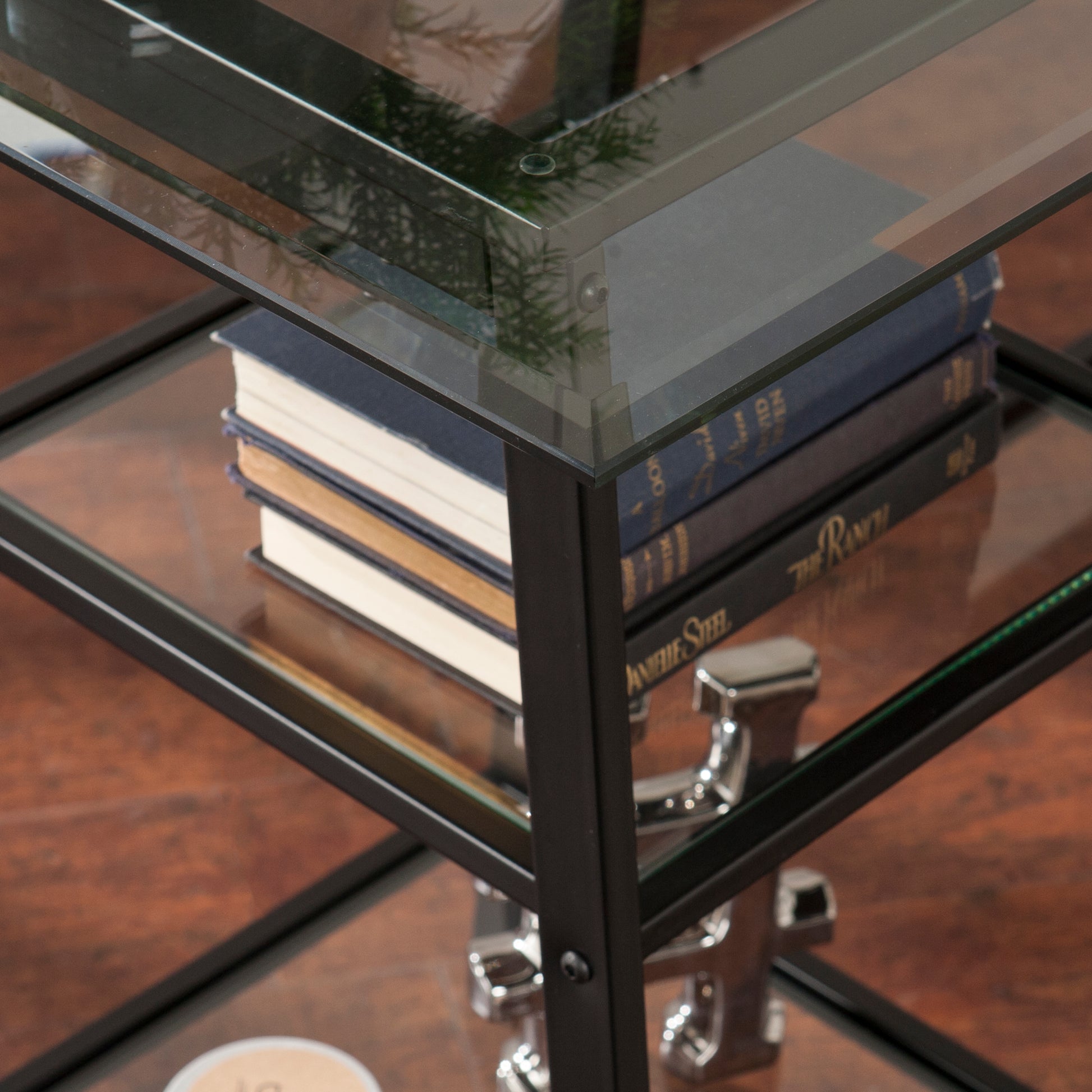 Black metal and glass end table with books and decorative anchor