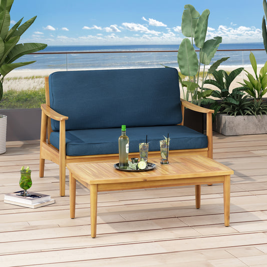 Acacia wood outdoor sofa with navy blue cushions and matching coffee table on a deck