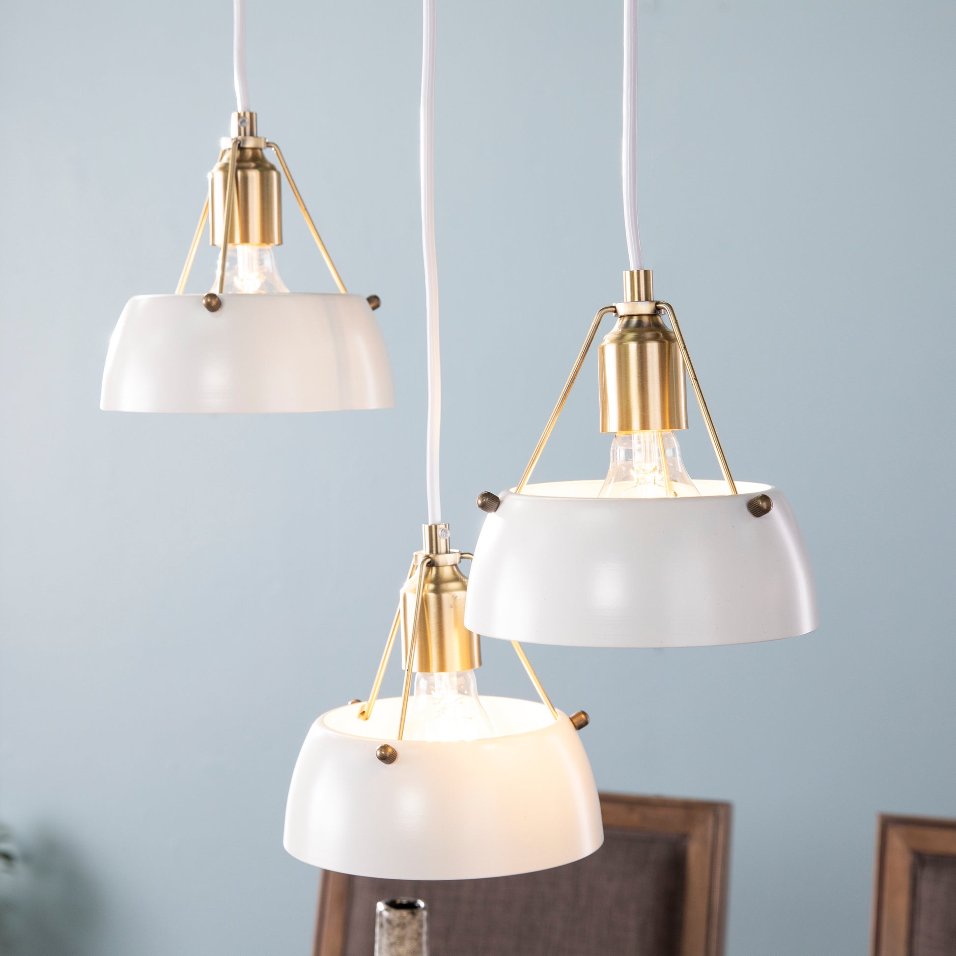 White dome pendant light with brass accents and exposed bulb