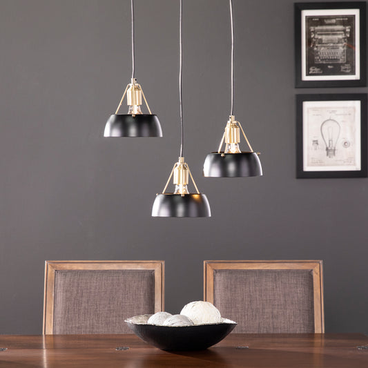 Three black dome pendant lights with brass accents hang above a dining table