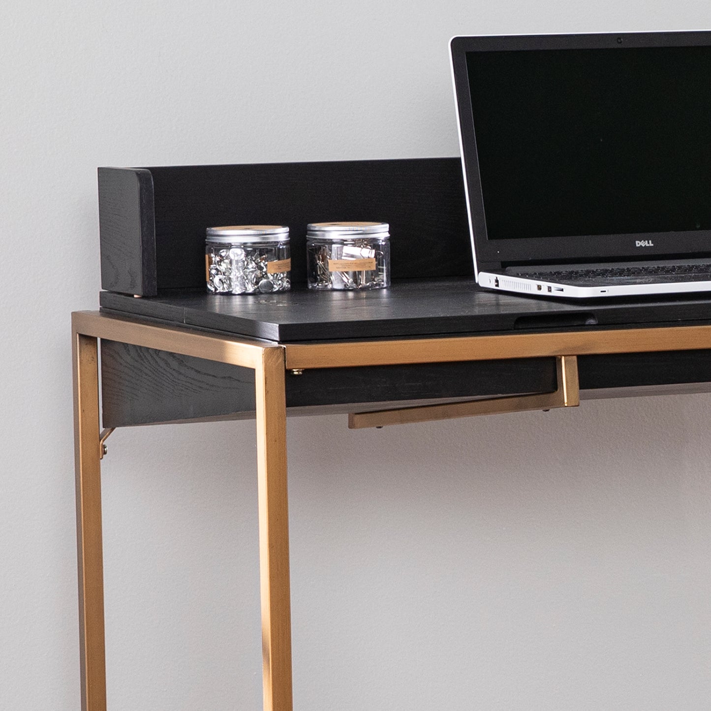 Modern black wooden desk with gold metal legs and a Dell laptop