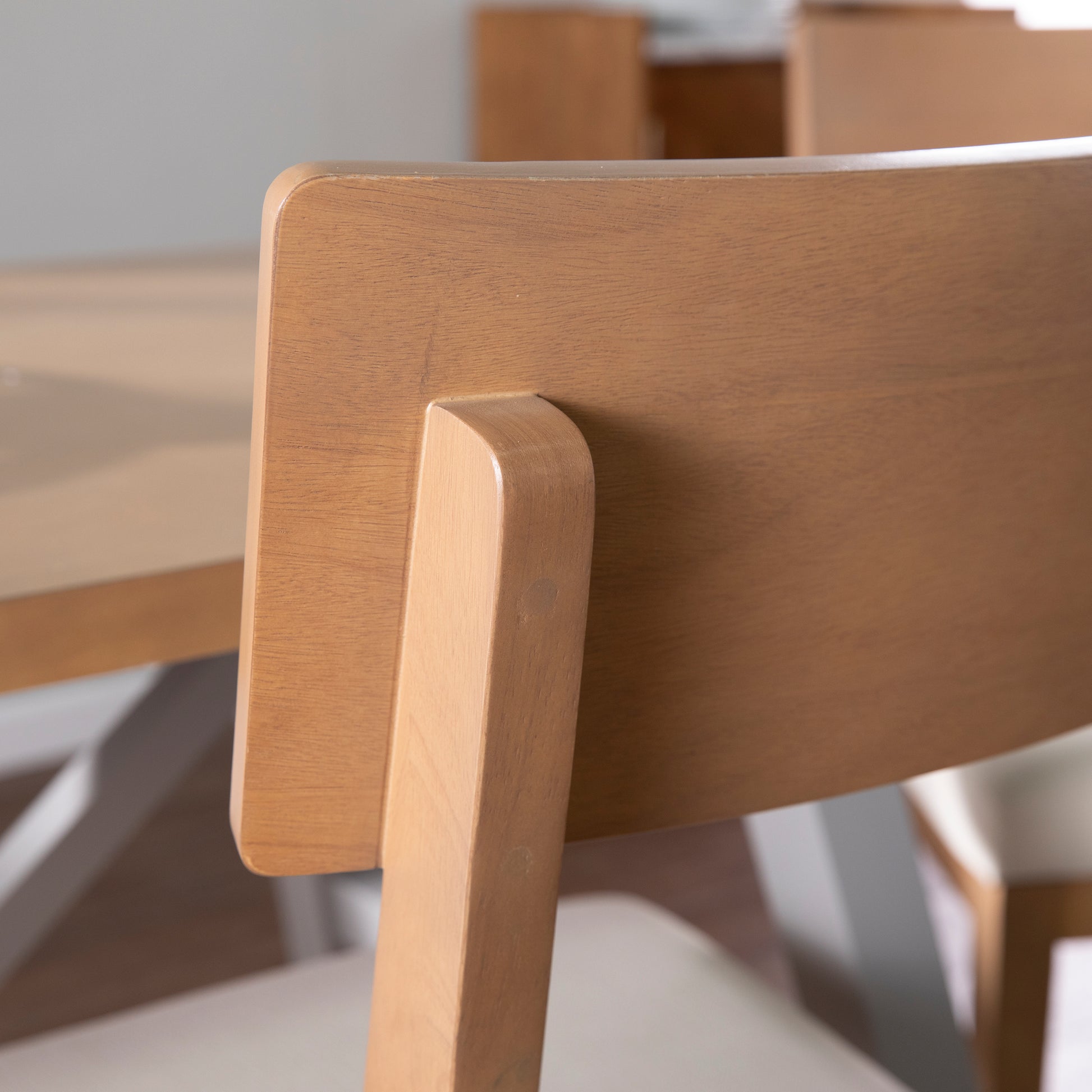 Closeup of a solid wood dining chair back with natural grain showing its modern design