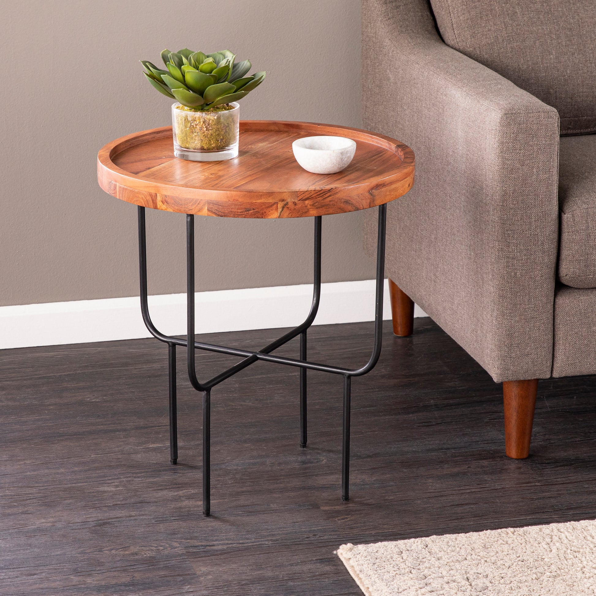 Round wood accent table with a plant and bowl featuring a wooden top and black metal legs