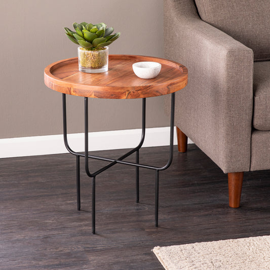 Round wood accent table with a plant and bowl featuring a wooden top and black metal legs
