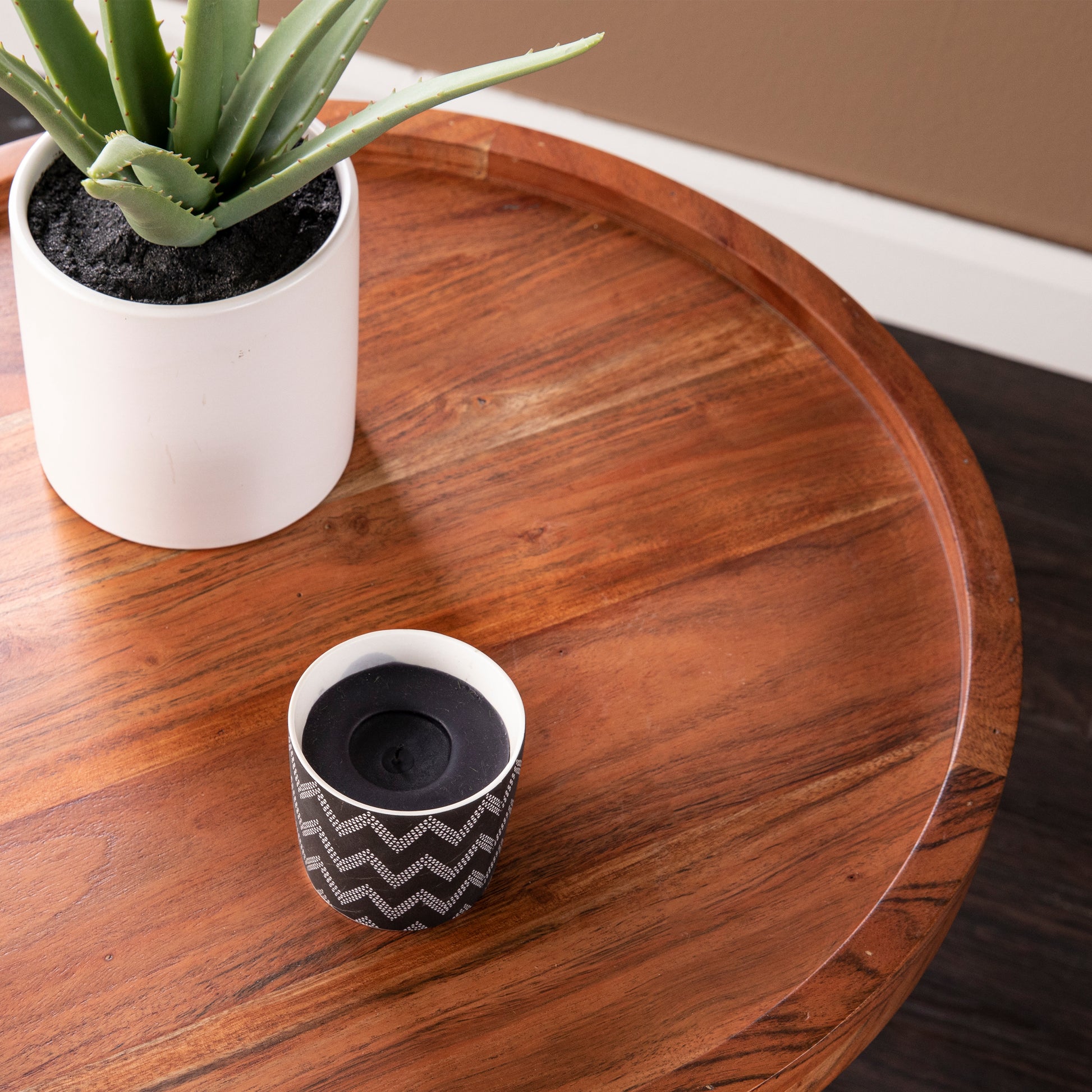 White ceramic pot with a green aloe vera plant on a wooden table