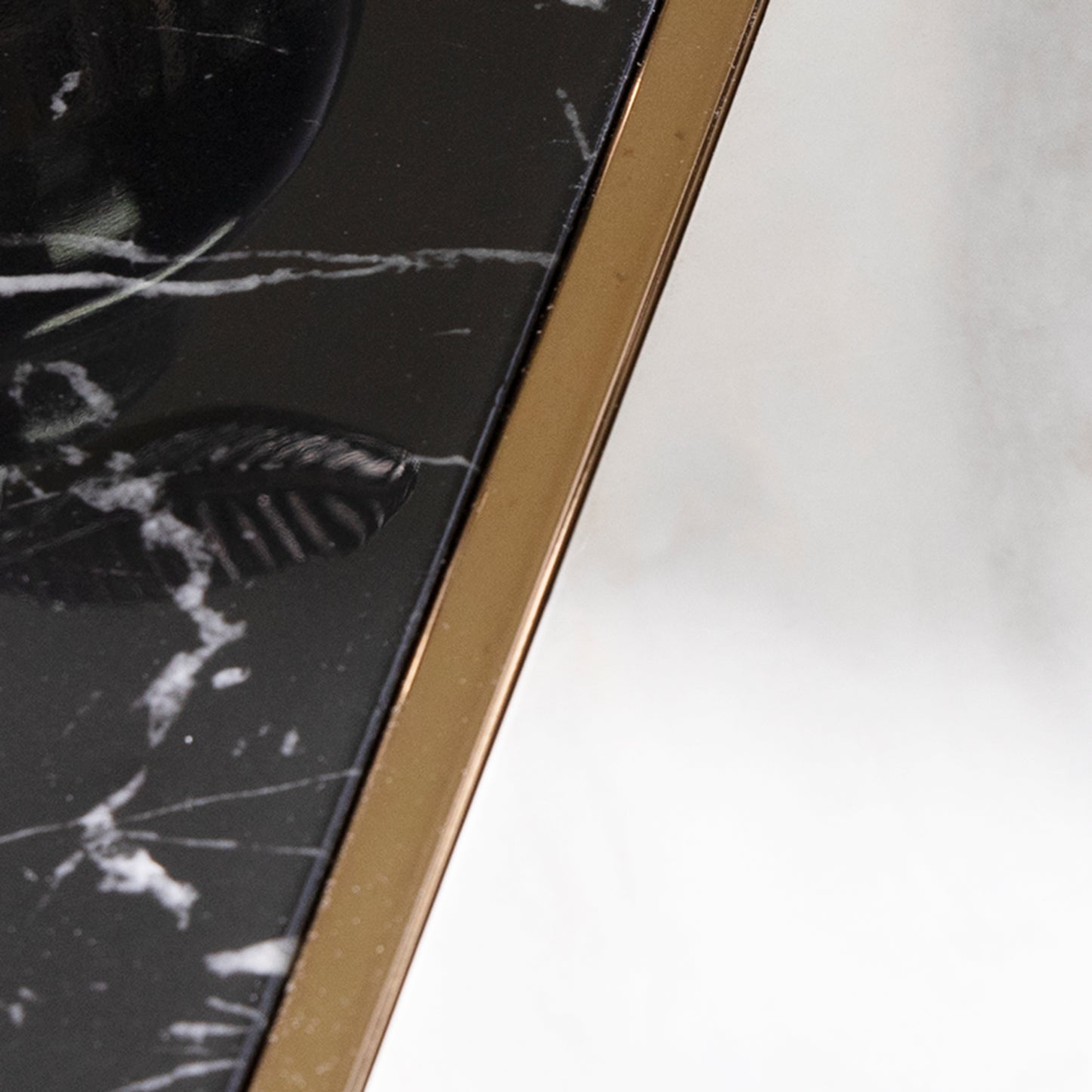 Closeup of a black marble surface with white veining accented by a gold metal edge