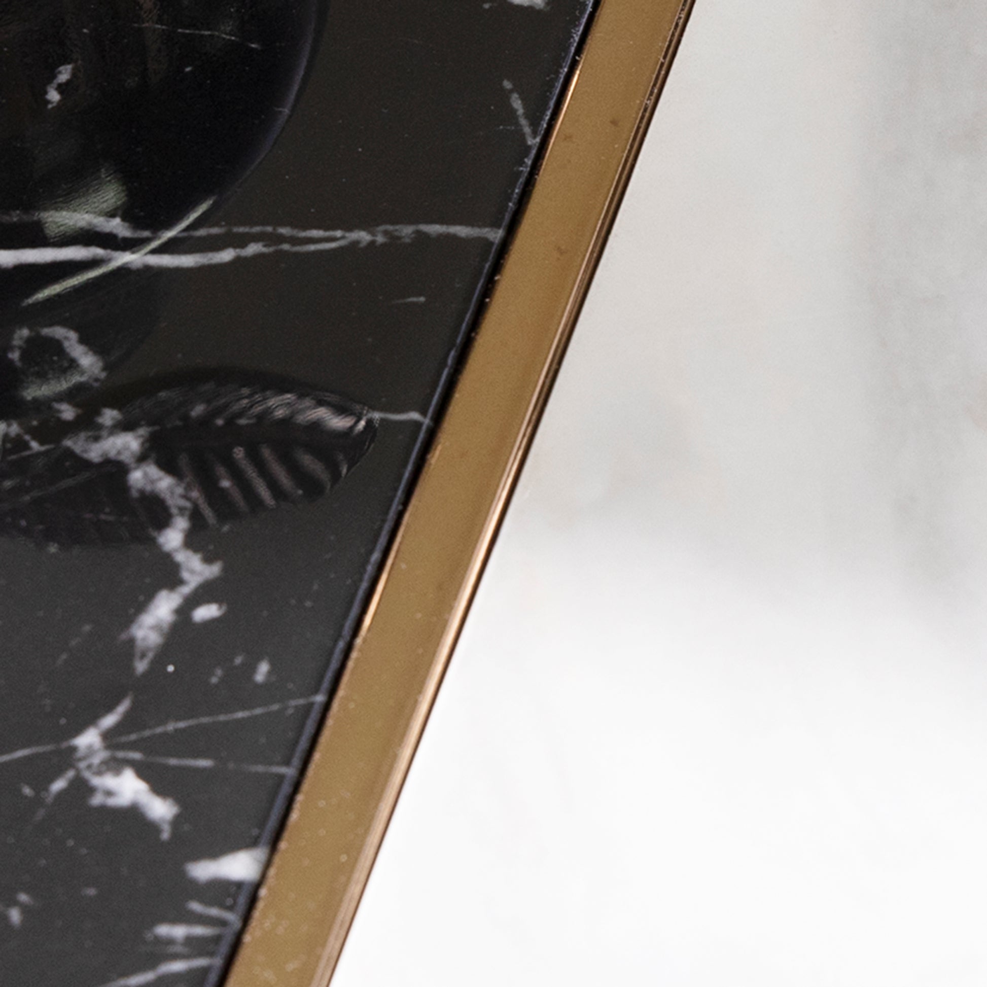 Closeup of a black marble surface with white veining accented by a gold metal edge
