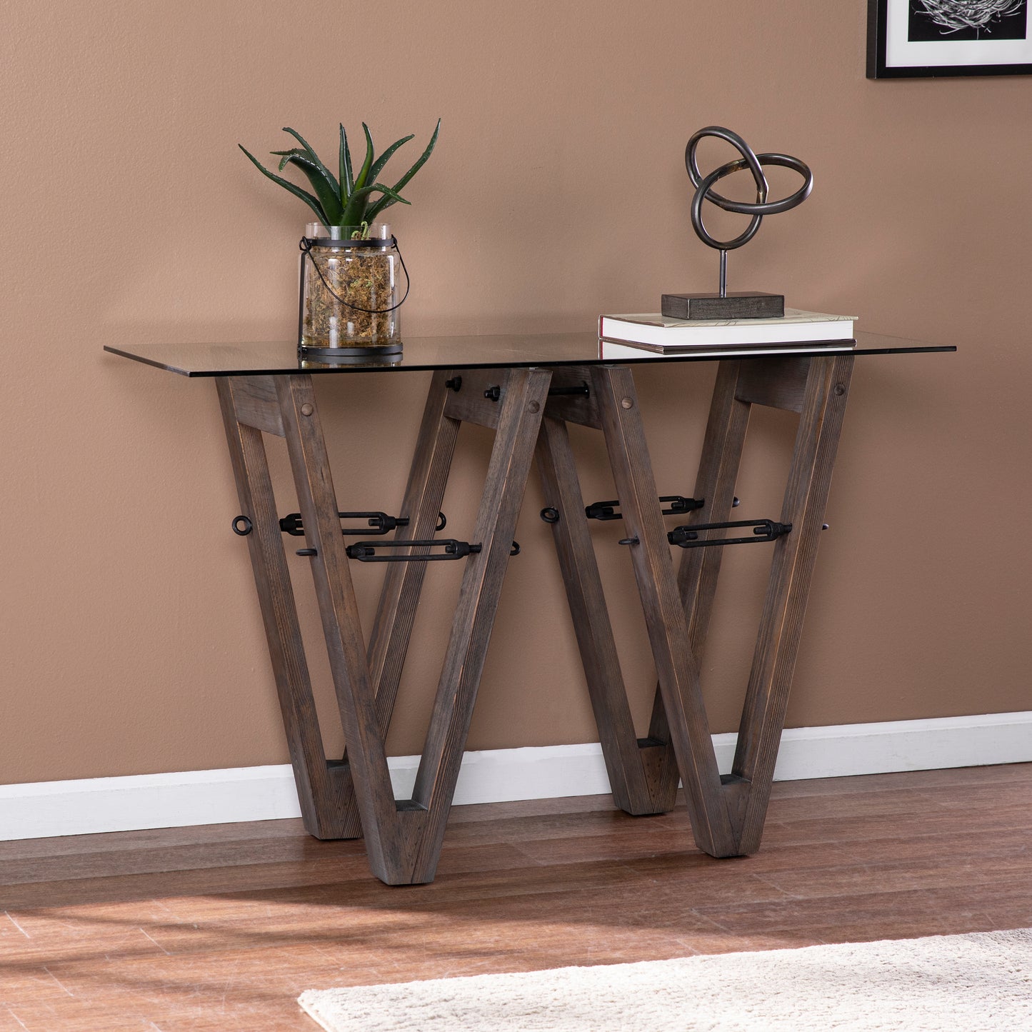 Rustic wooden console table with glass top featuring geometric legs and metal accents for entryways