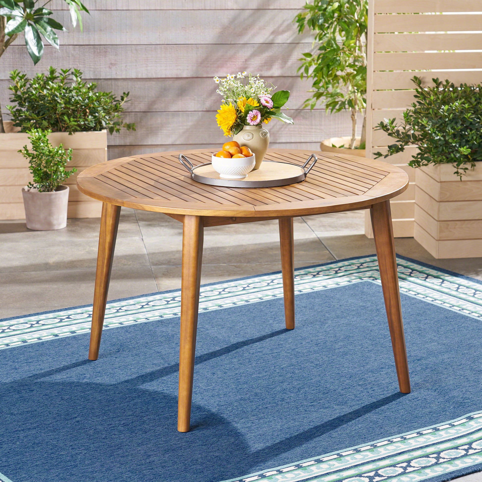Round wooden patio dining table with slatted top and tapered legs