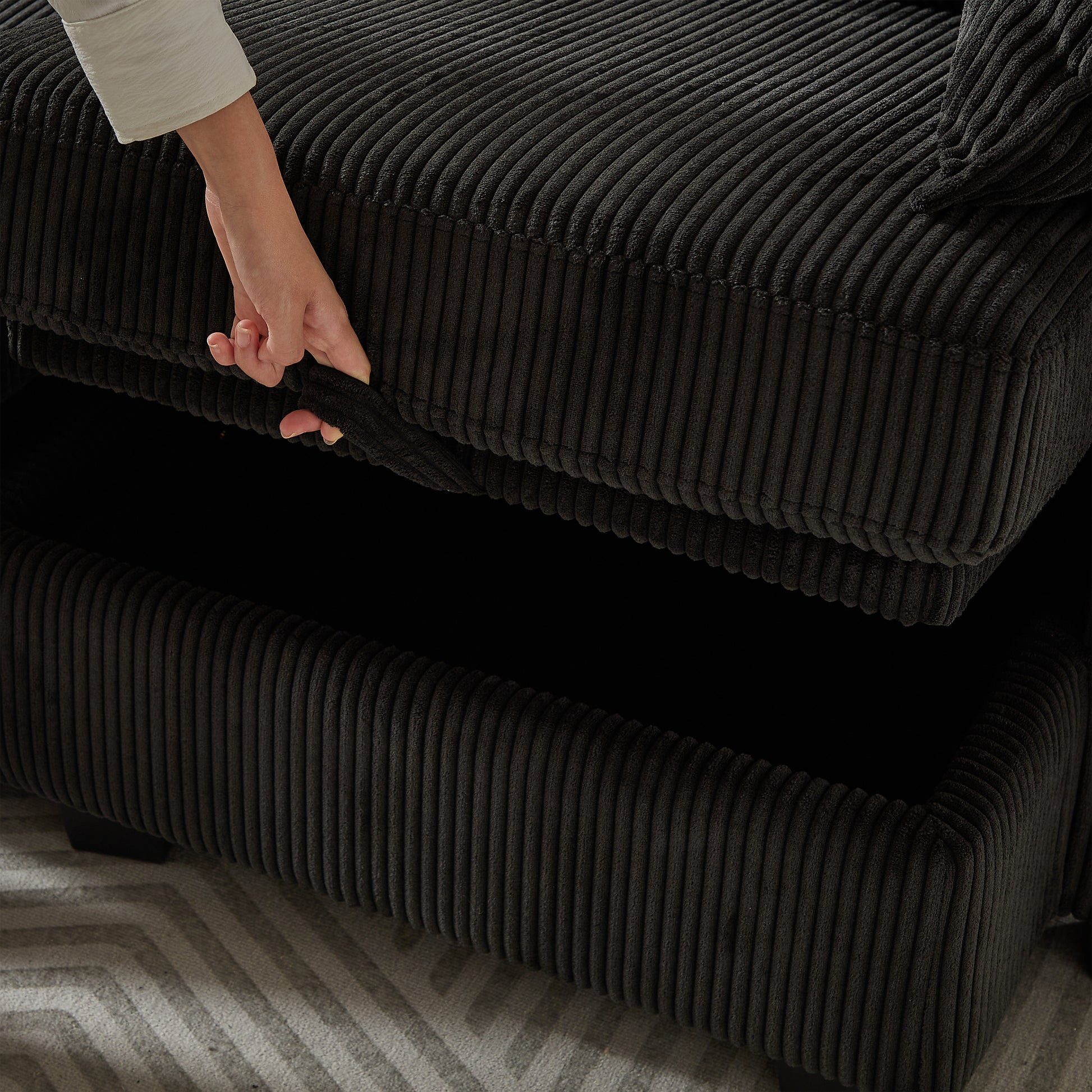 Black corduroy sofa with hidden storage compartment being accessed
