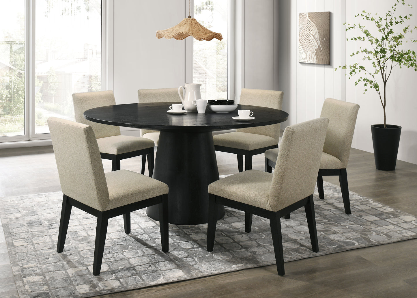 Round black dining table with pedestal base and four neutral upholstered chairs