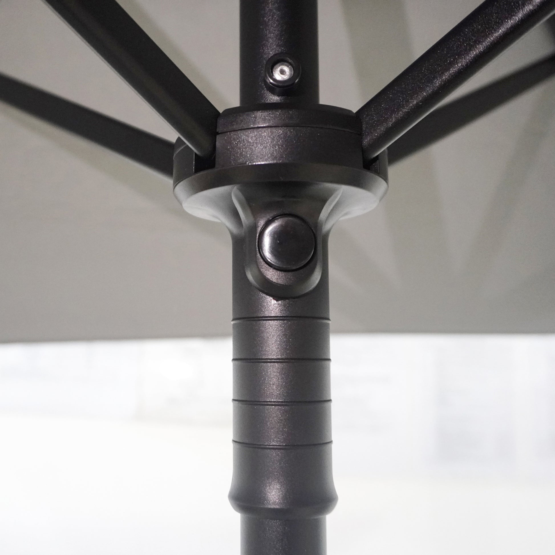 Closeup of black aluminum patio umbrella pole with a white canopy frame