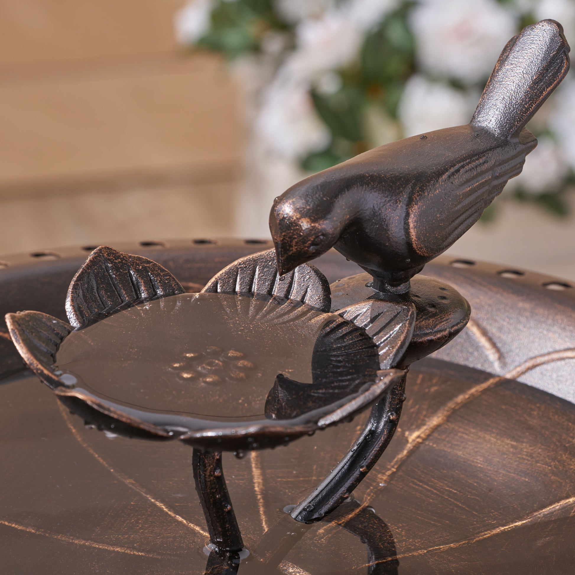 Ornate bronze bird bath with detailed floral petal basin and perched bird accent